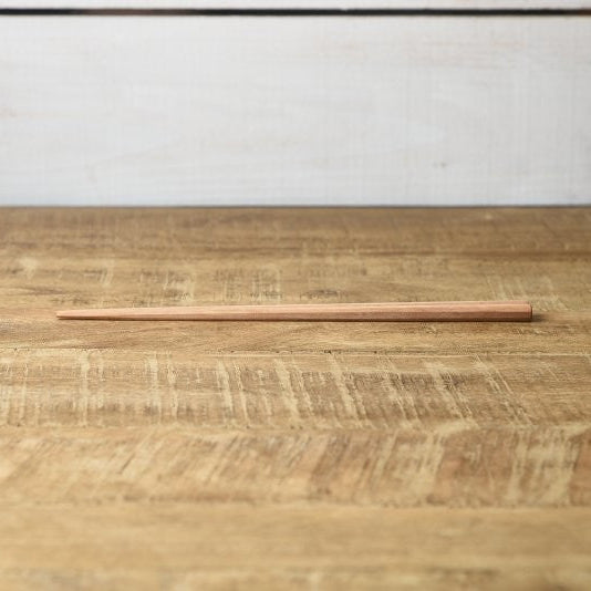 Single Kawai Tetoca Chopstick made from prune wood, laid flat on wooden surface, showing minimalist design and natural wood grain.