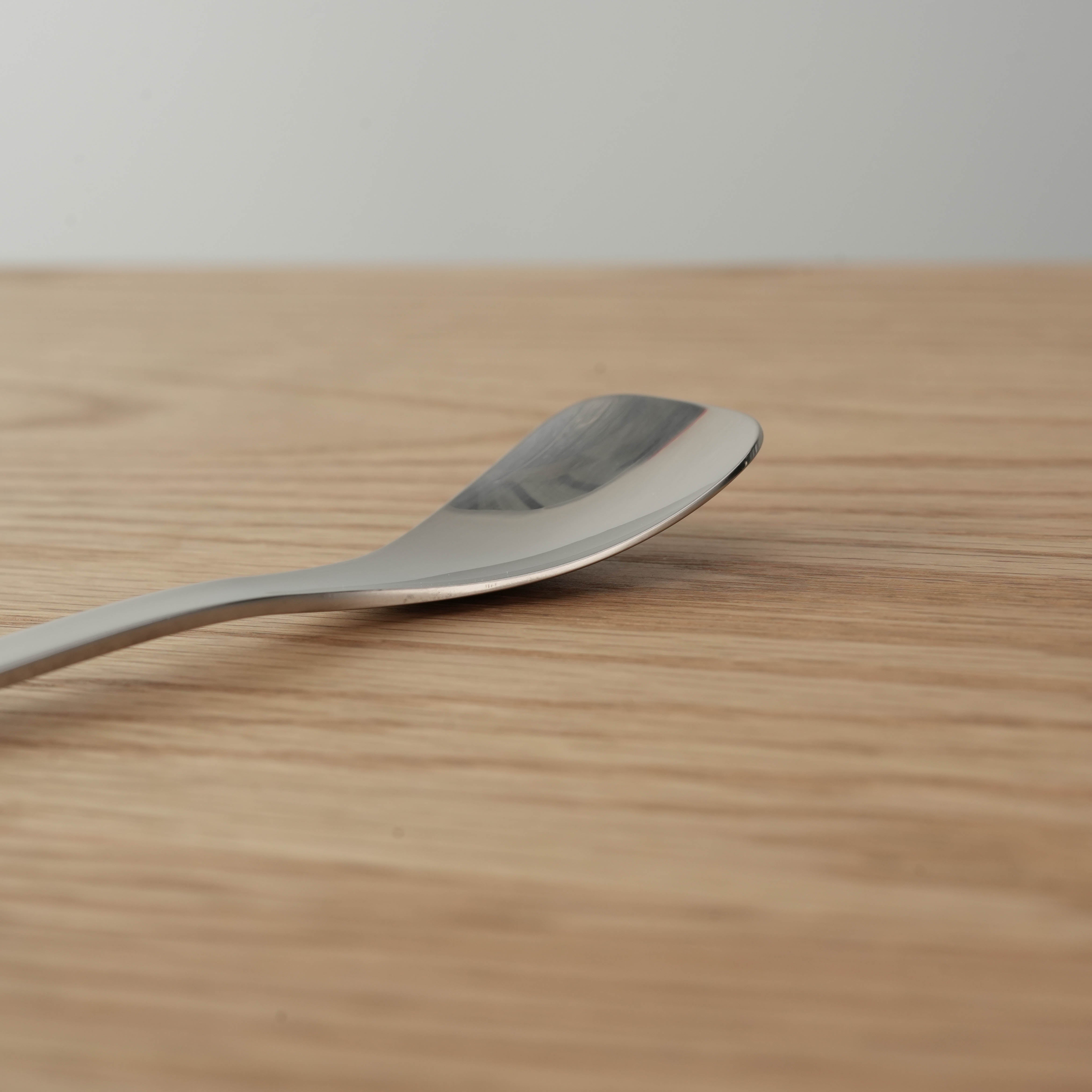 Close-up of Sori Yanagi stainless steel ice cream spoon showing curved design and smooth edges. Premium 18-8 stainless steel kitchen utensil.