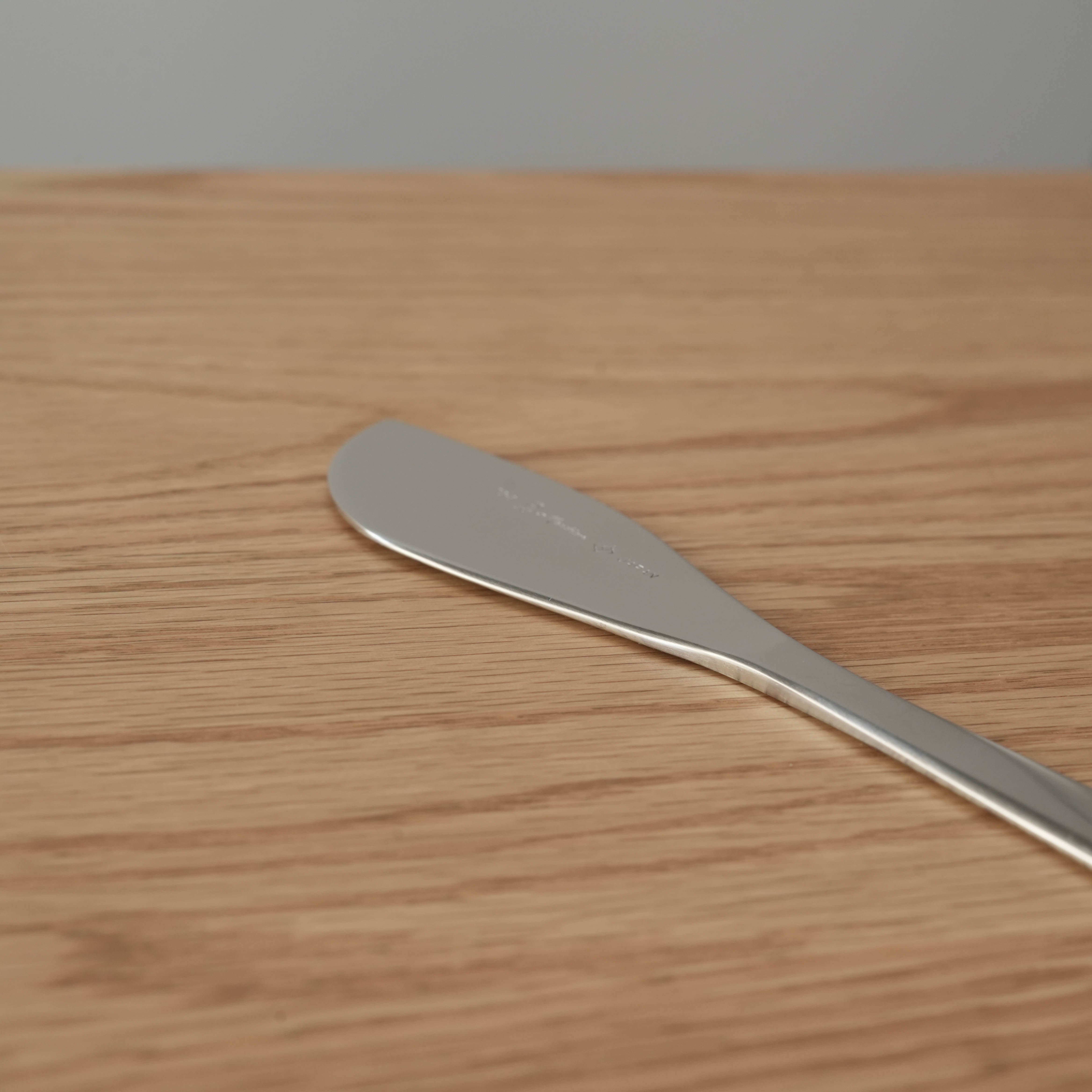 Close-up of Sori Yanagi stainless steel butter knife showing unique blade shape. Premium Japanese kitchen utensil for precise spreading.