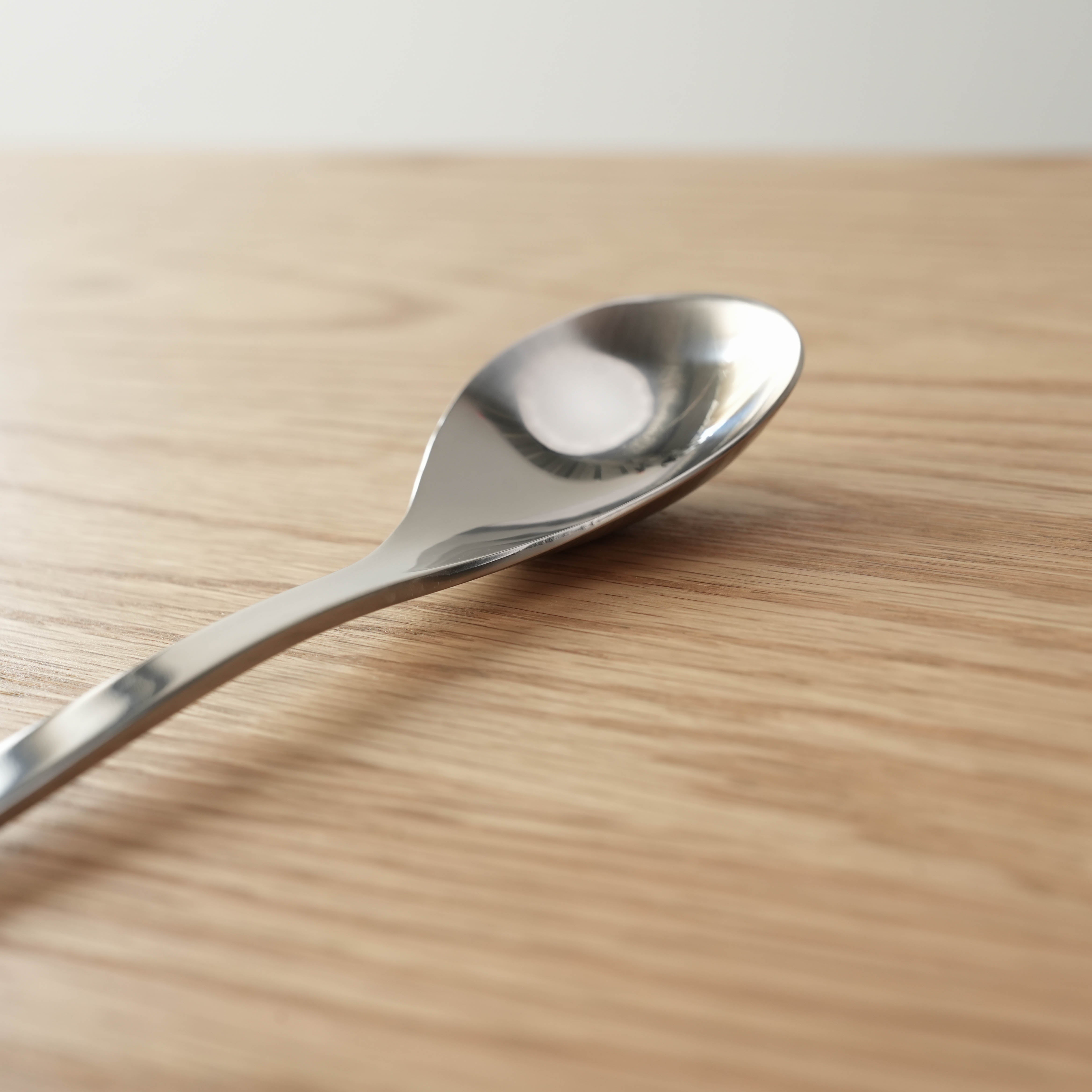 Sori Yanagi Stainless Steel Table Spoon with seamless design on wooden surface. 183mm length, 42g weight, ideal for everyday kitchen use.
