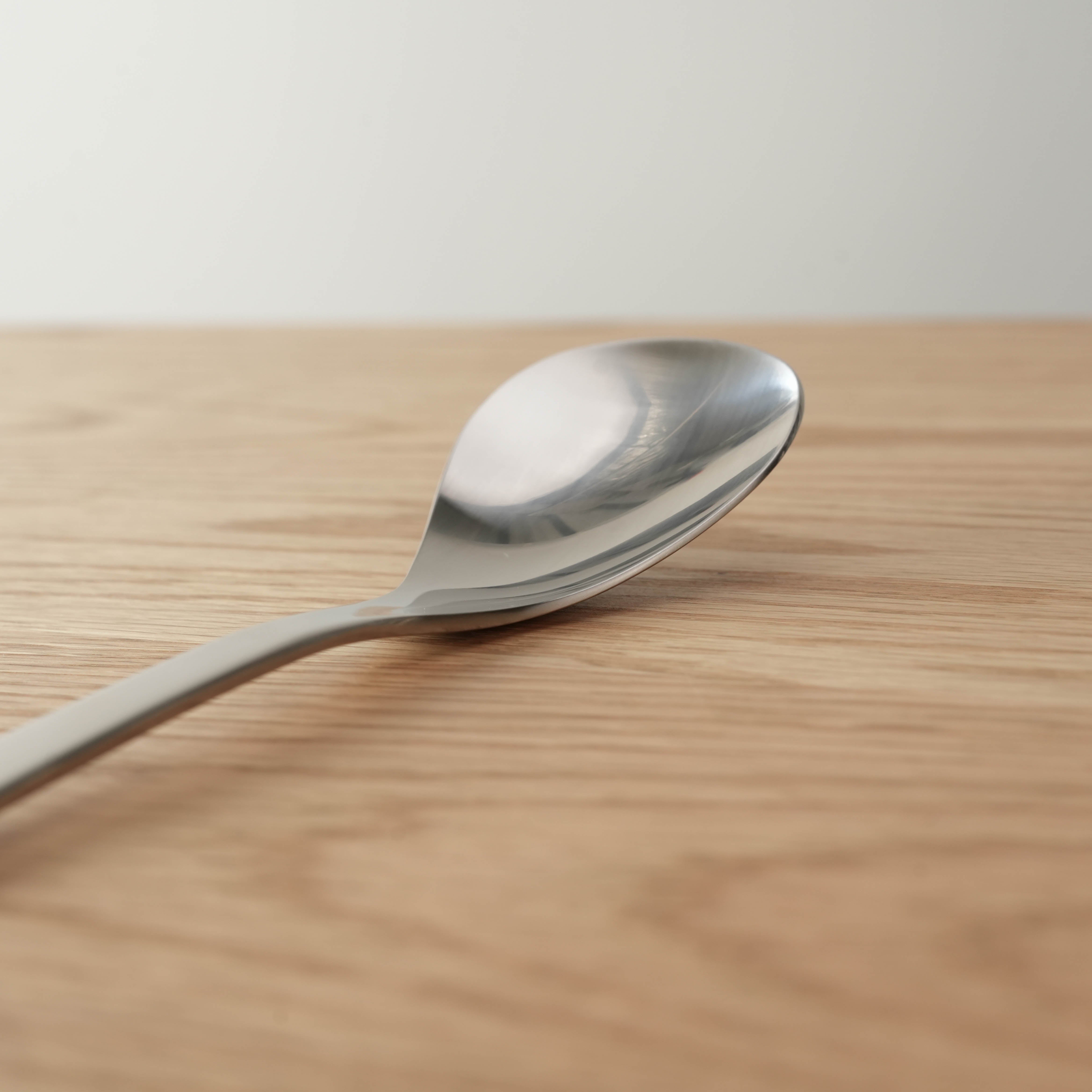 Close-up of Sori Yanagi Stainless Steel Salad Spoon 22cm showcasing its smooth, ergonomic bowl and polished finish for stylish table presentation.