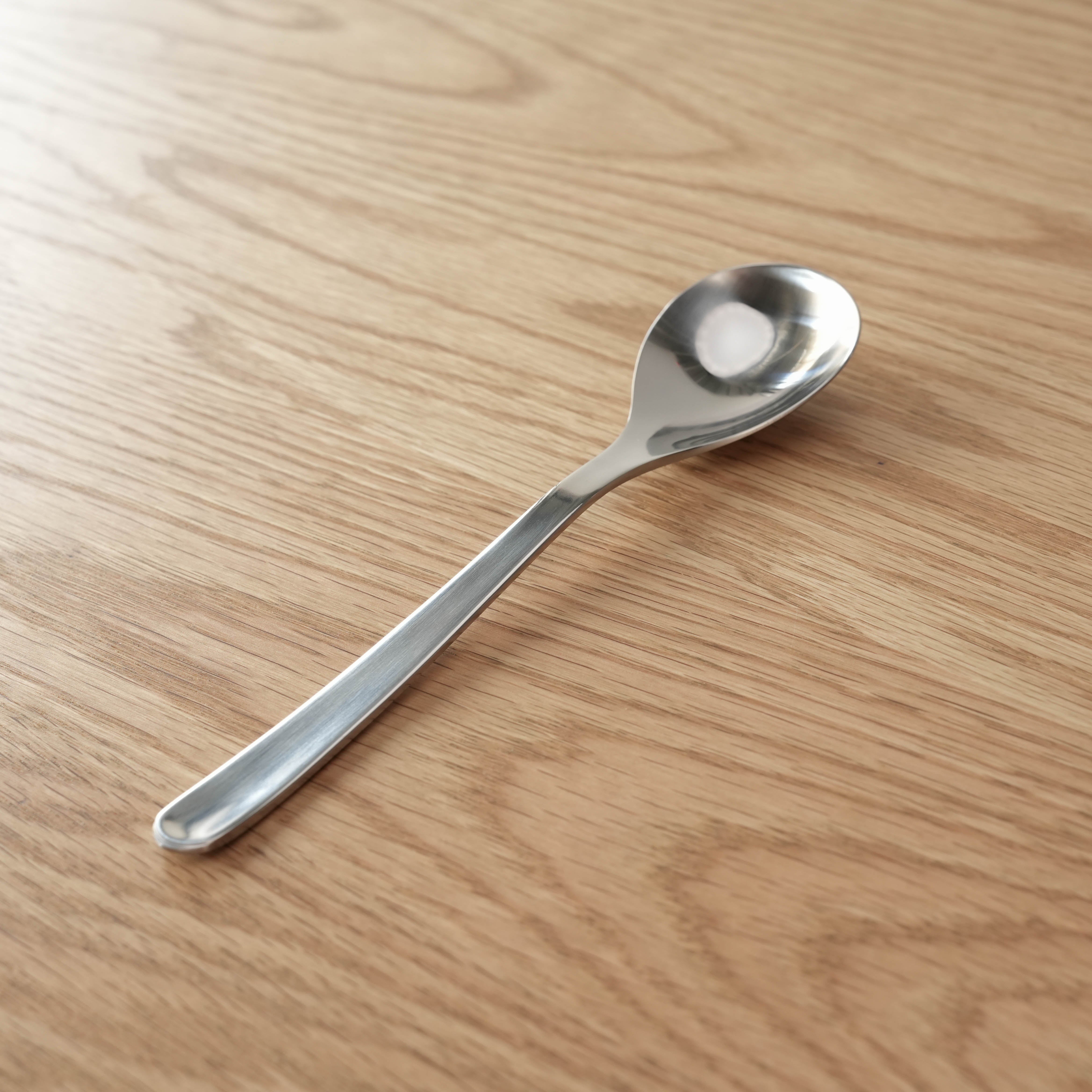 Sori Yanagi stainless steel spoon with elegant curved handle, ideal for desserts and modern kitchen settings.