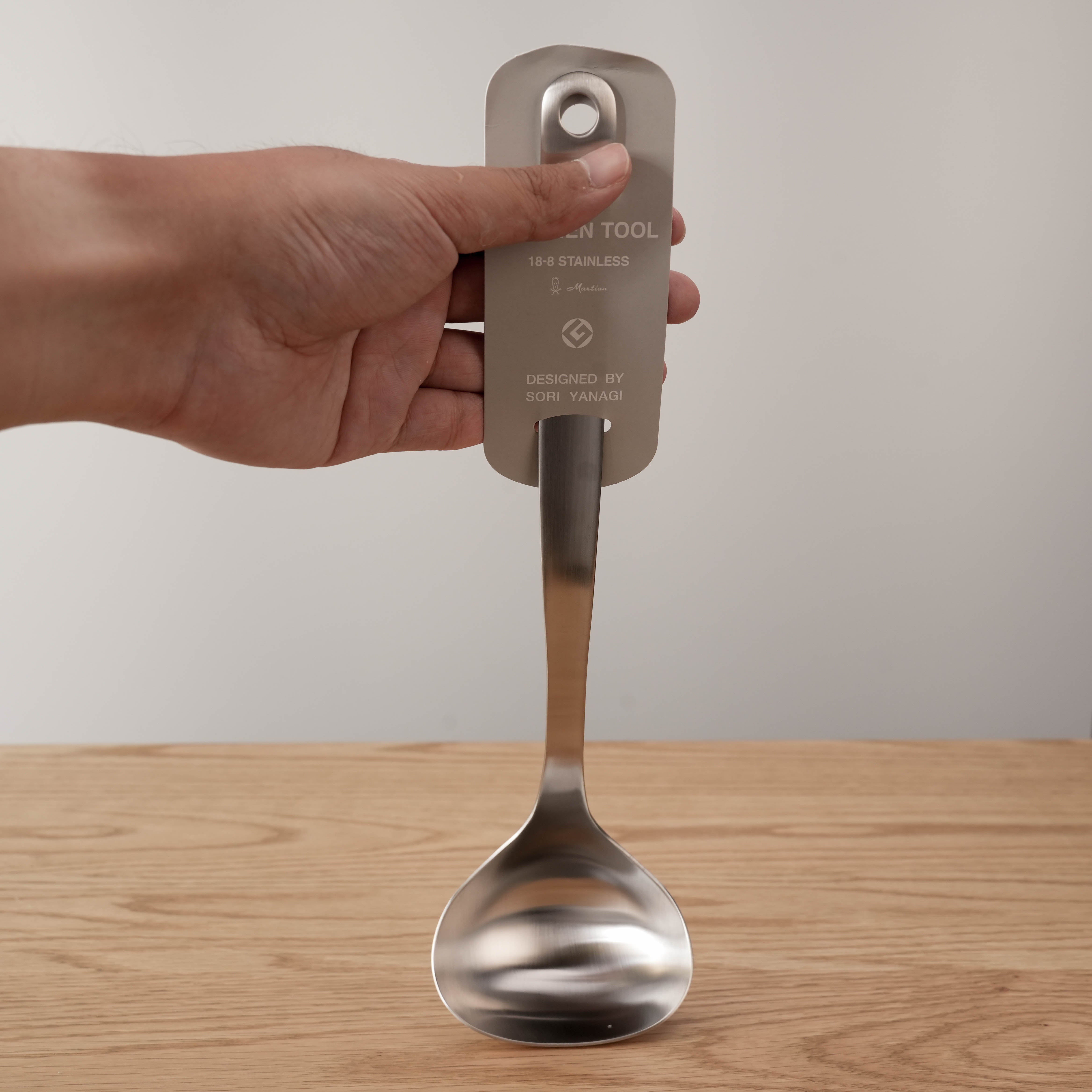 Front view of Sori Yanagi ladle with wide bowl and stainless steel finish, labeled for quality and dishwasher safety.