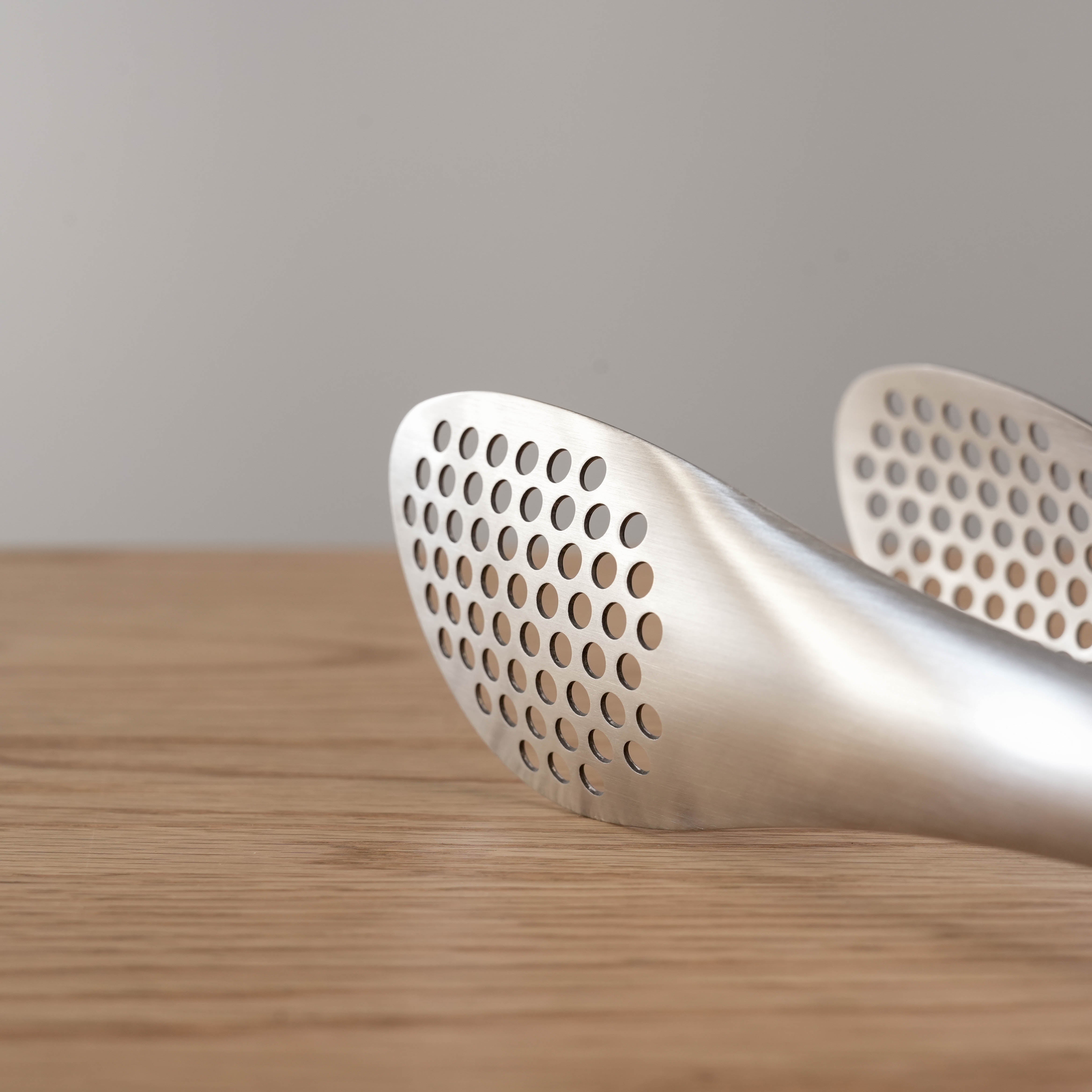 Close-up of Sori Yanagi Stainless Steel Tongs highlighting the precision perforations ideal for straining and serving in modern kitchens.