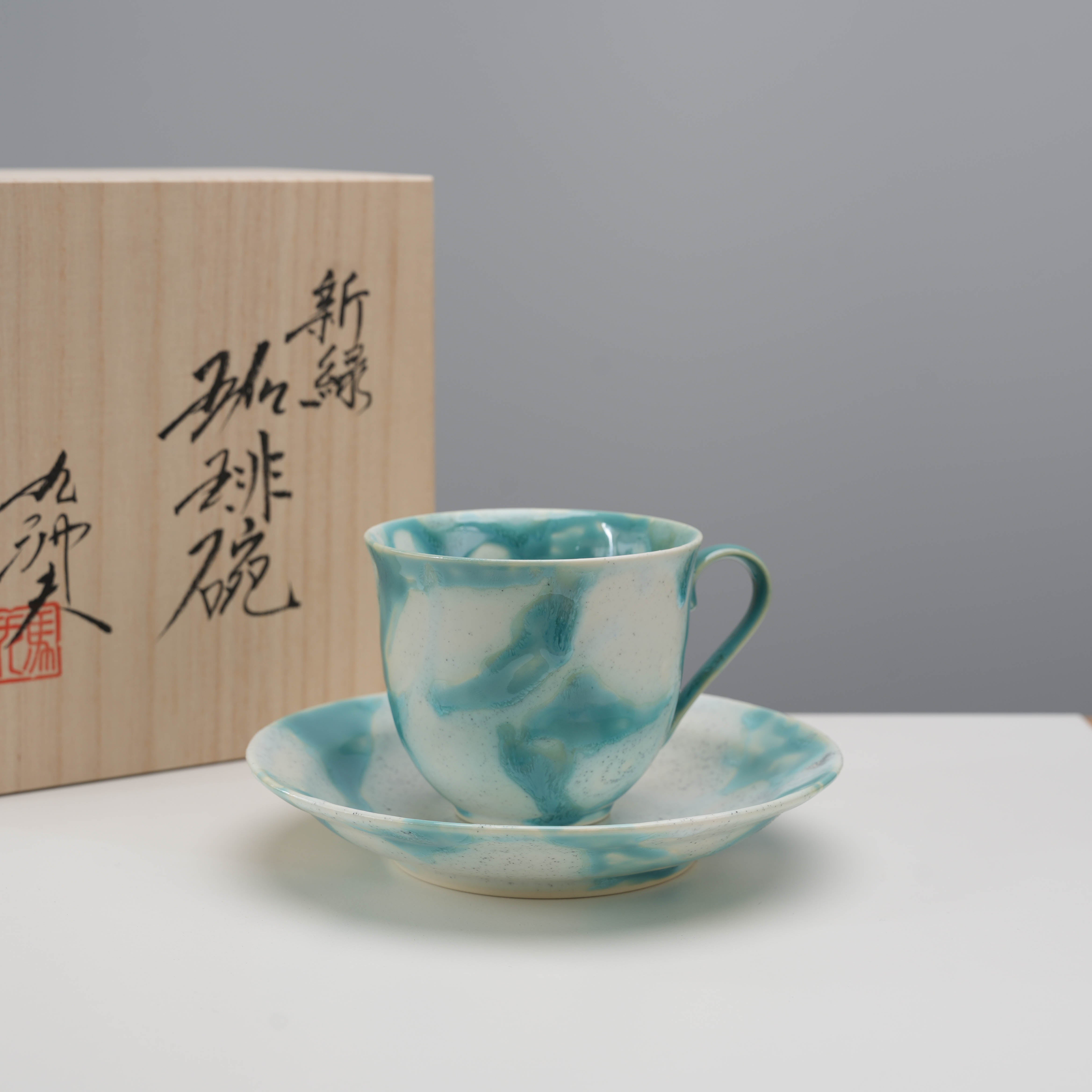 Arita Ware Shinryo New Green Coffee Cup & Saucer Set displayed with traditional wooden box, highlighting Japanese craftsmanship.