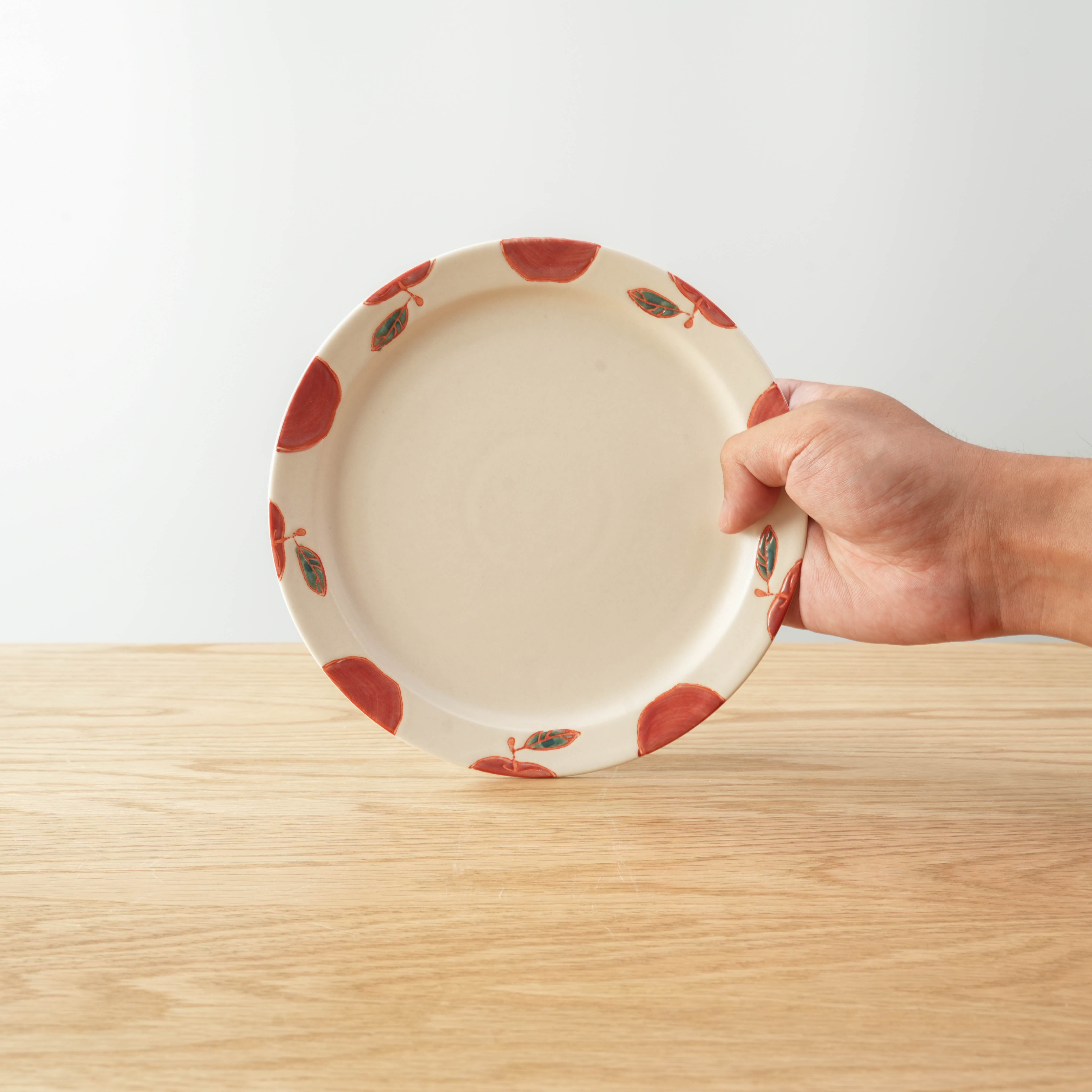 Hasami Ware Apple Plate held in hand, showcasing its medium round shape and red apple design. Ideal for stylish Japanese-inspired dining.