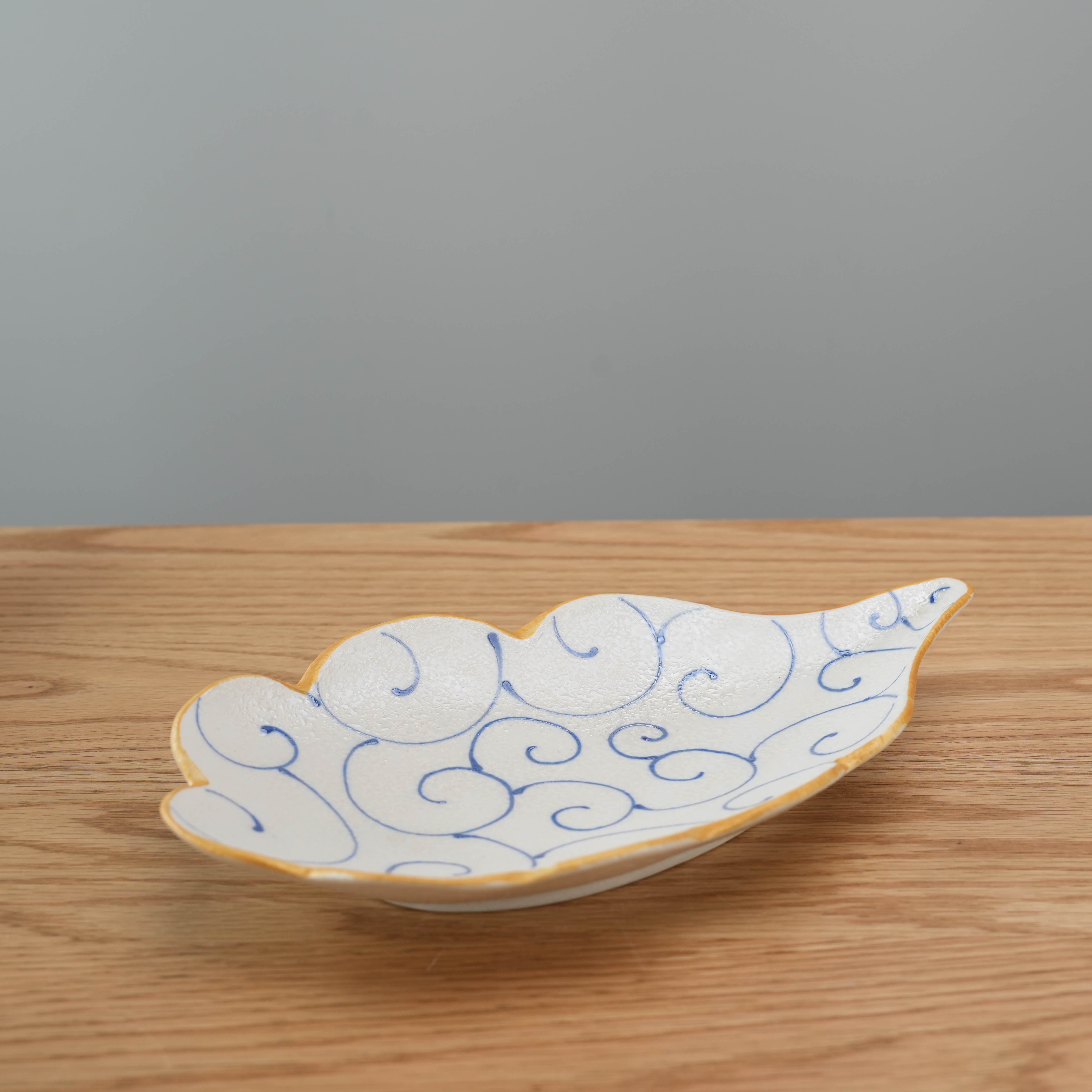 Hirado Ware Cloud Plate for Serving in blue arabesque design, shaped like a cloud with a textured glaze and yellow rim, ideal for sauces or decor.