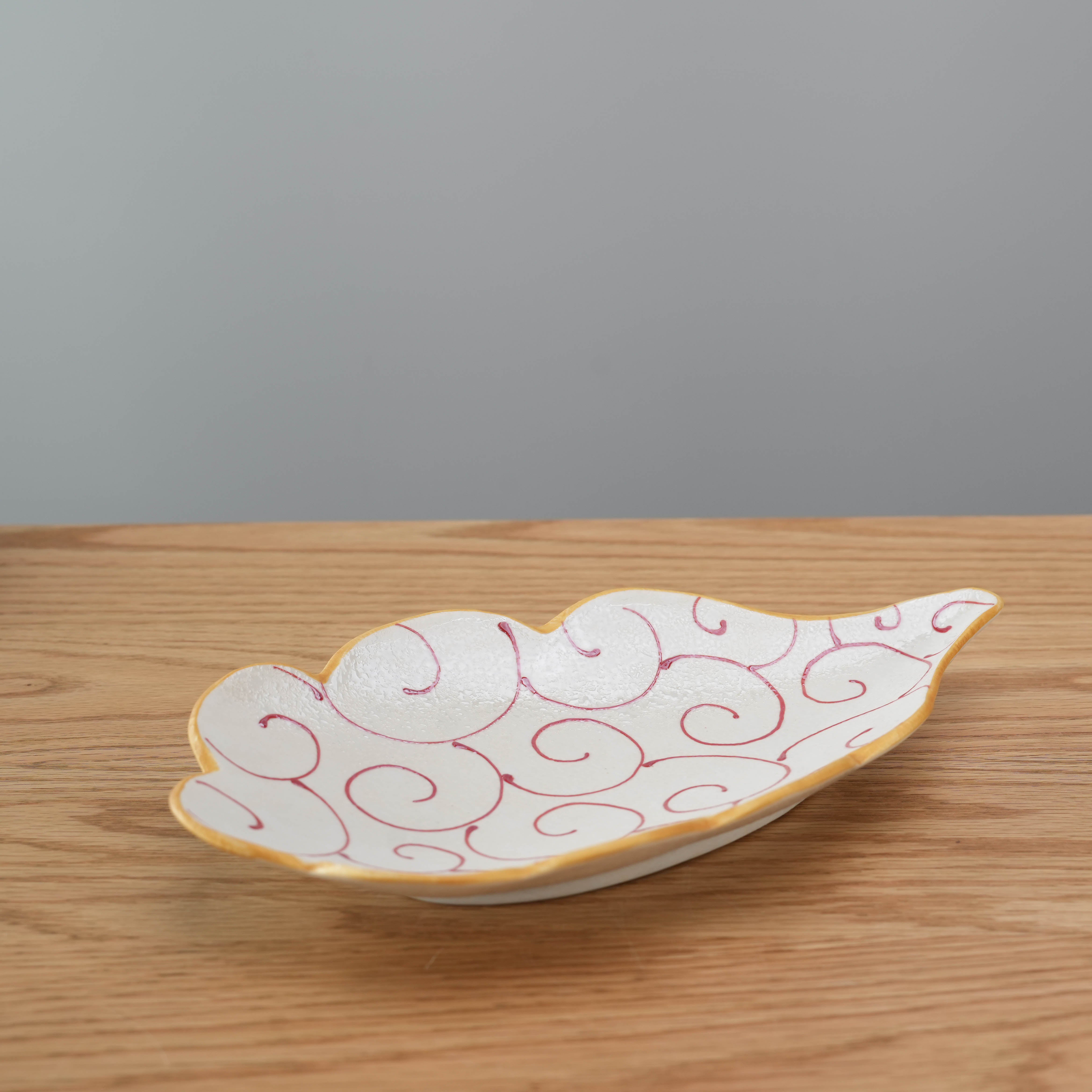 Japanese Hirado Ware Cloud Plate featuring red arabesque swirls and a cloud-shaped form, perfect for elegant table settings or side dishes.