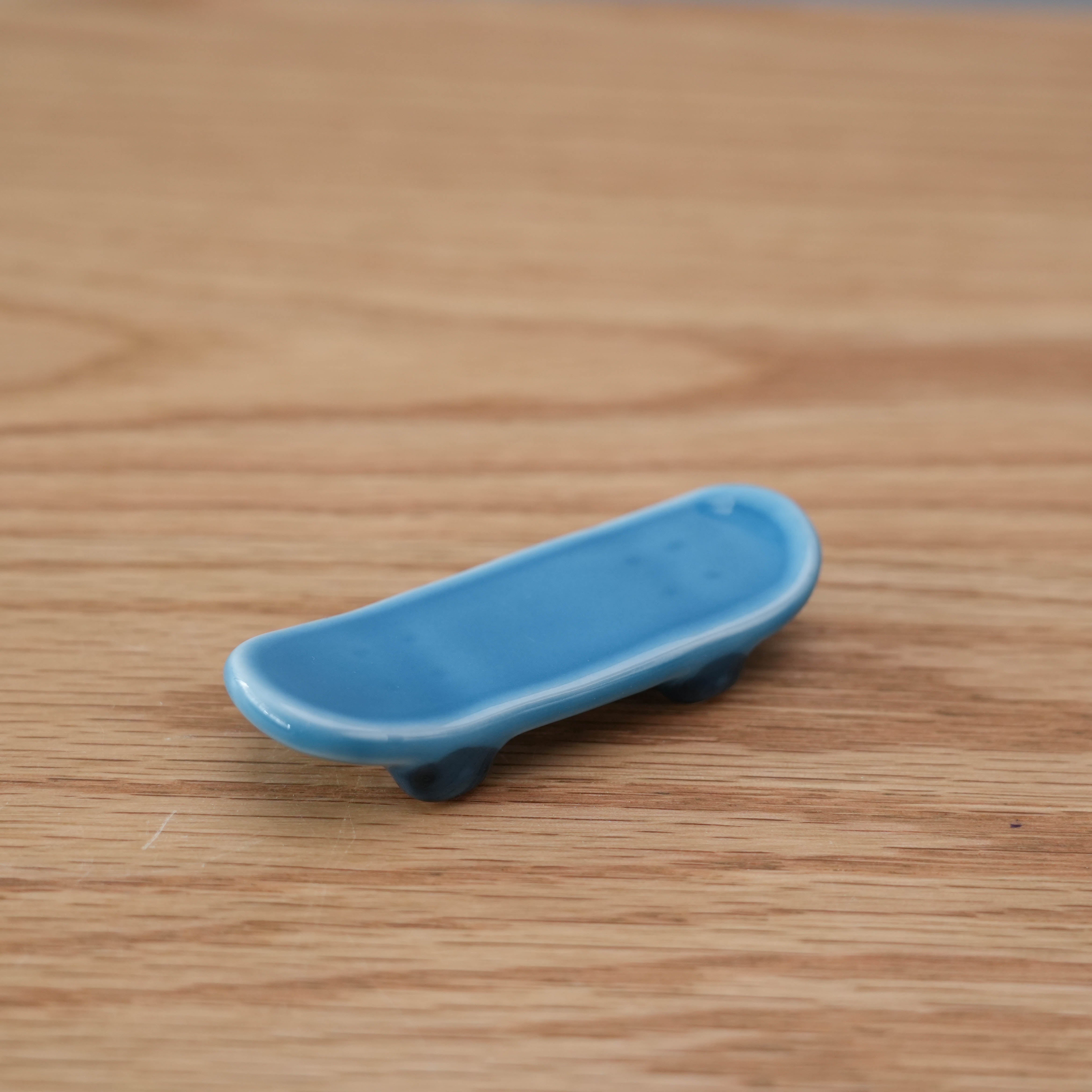 Close-up of Arita Ware Skateboard Chopstick Rest, showcasing its sleek blue finish and curved skateboard design, ideal for modern dining.