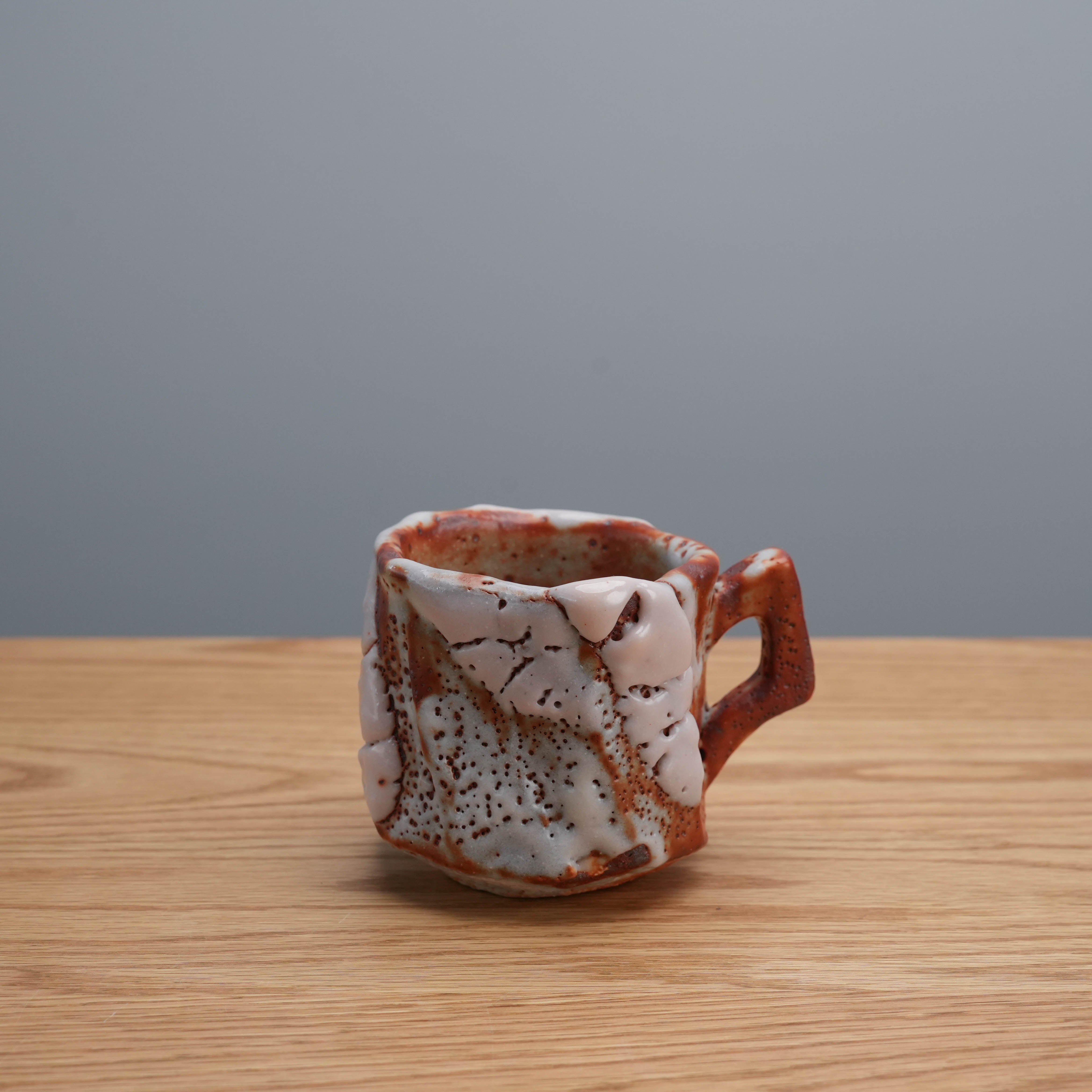 Kano Shinji Mino Ware Cup with red Shino glaze and angular handle, showcasing Japanese ceramic artistry in drinkware design.