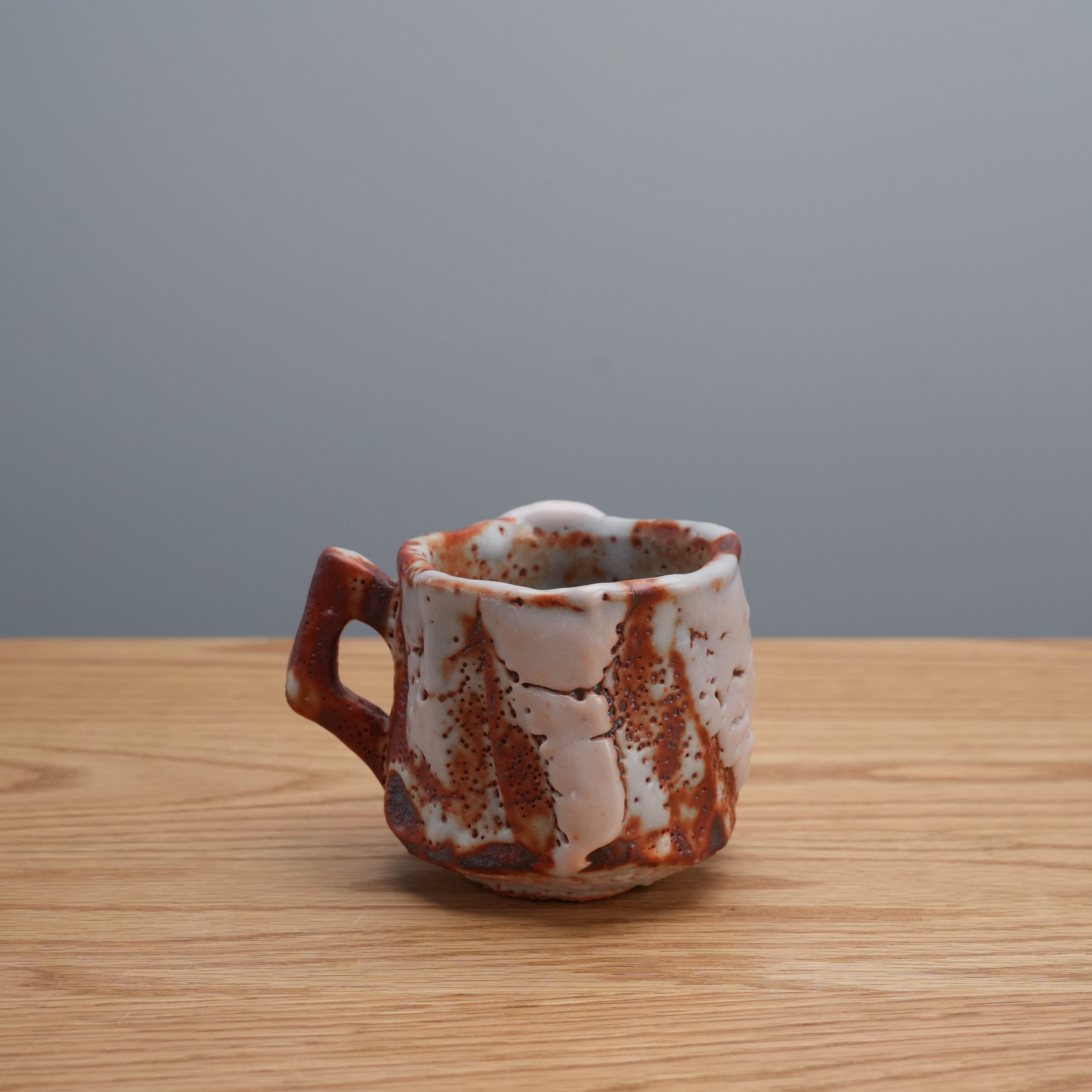 Side profile of red Shino handle cup by Kano Shinji, featuring organic form and traditional Mino Ware craftsmanship.