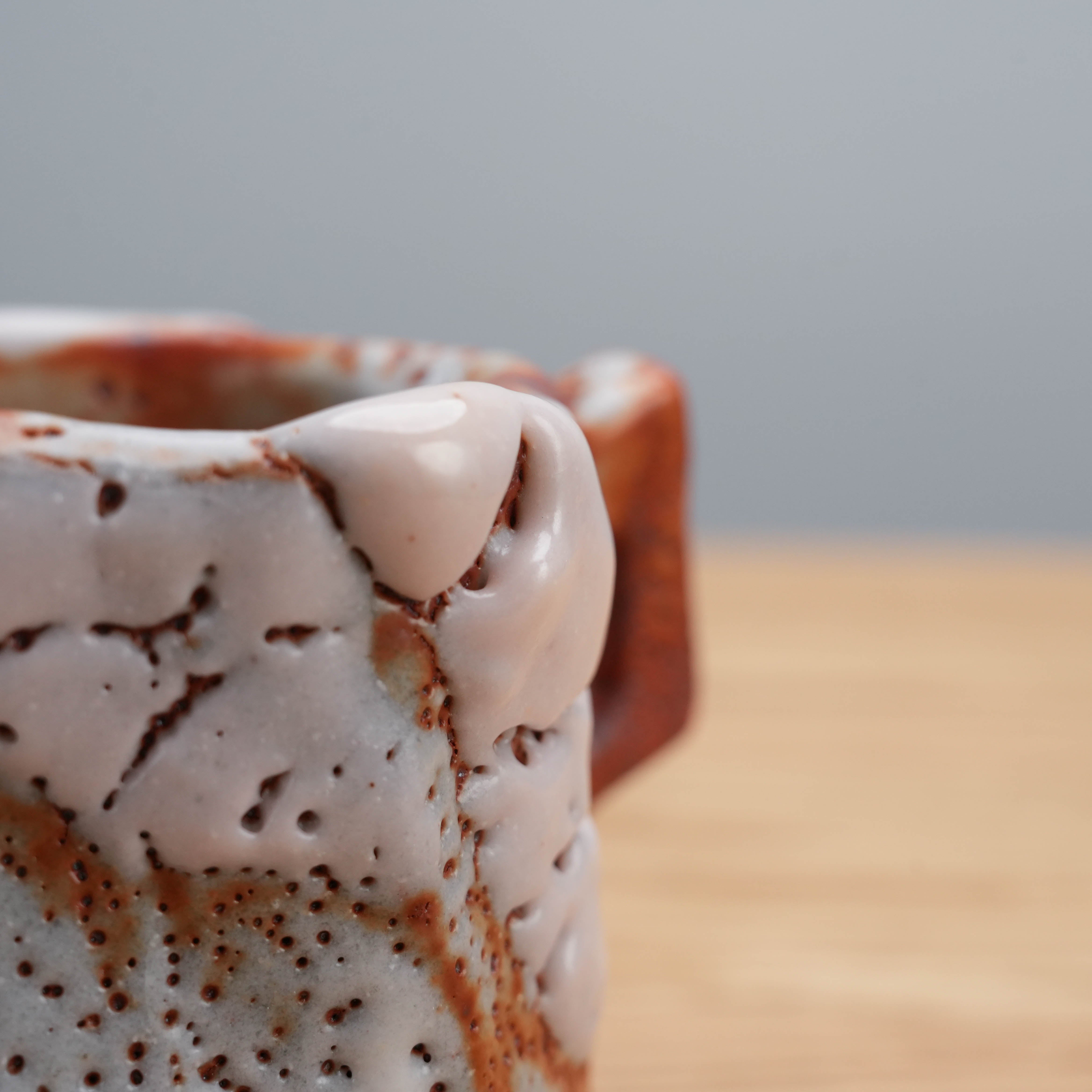 Detail of Shino glaze drips on Mino Ware cup by Kano Shinji, emphasizing wabi-sabi imperfections and ceramic artistry.