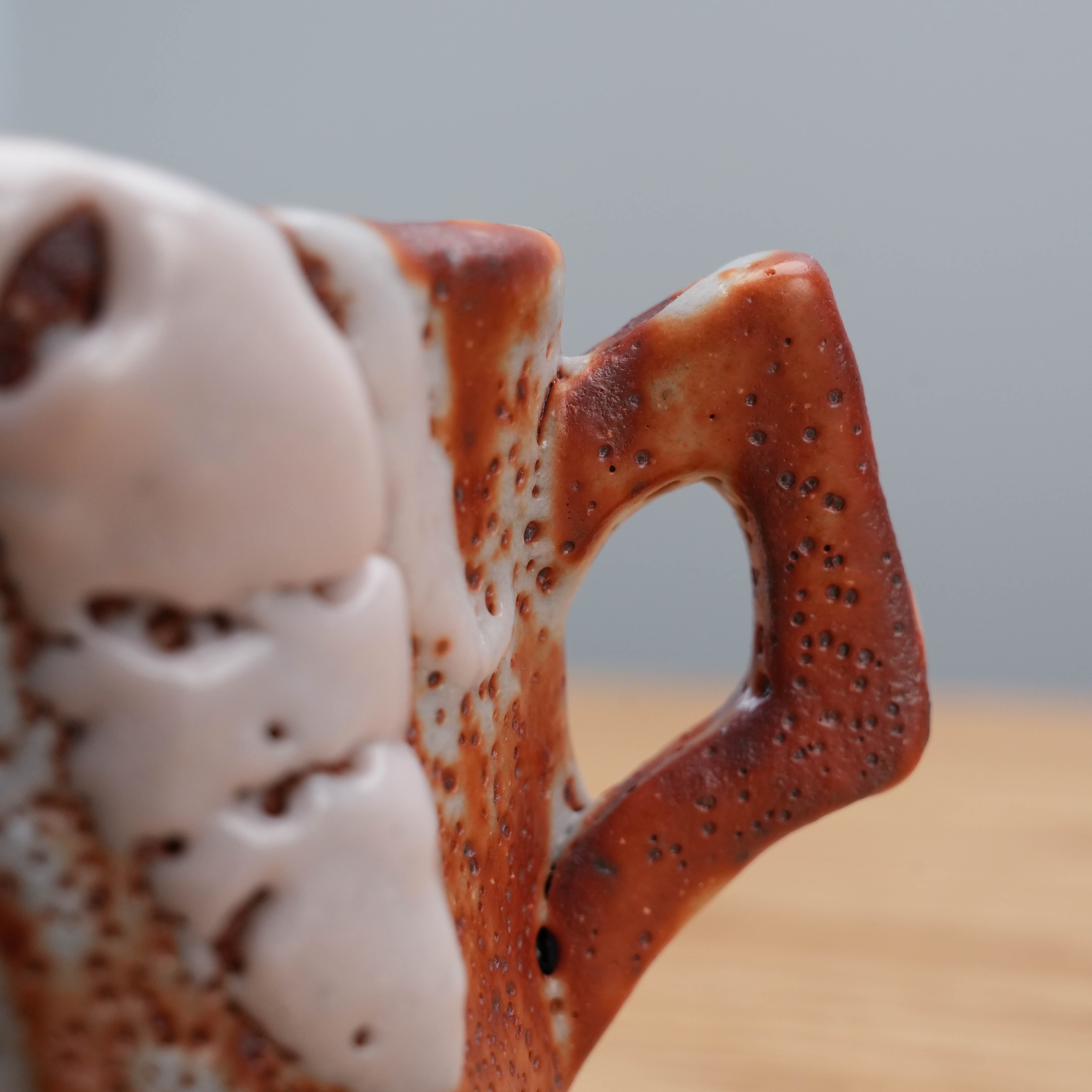 Close-up of the handle on the Kano Shinji Mino Ware Cup, showing textured red Shino glaze and artisanal ceramic detail.