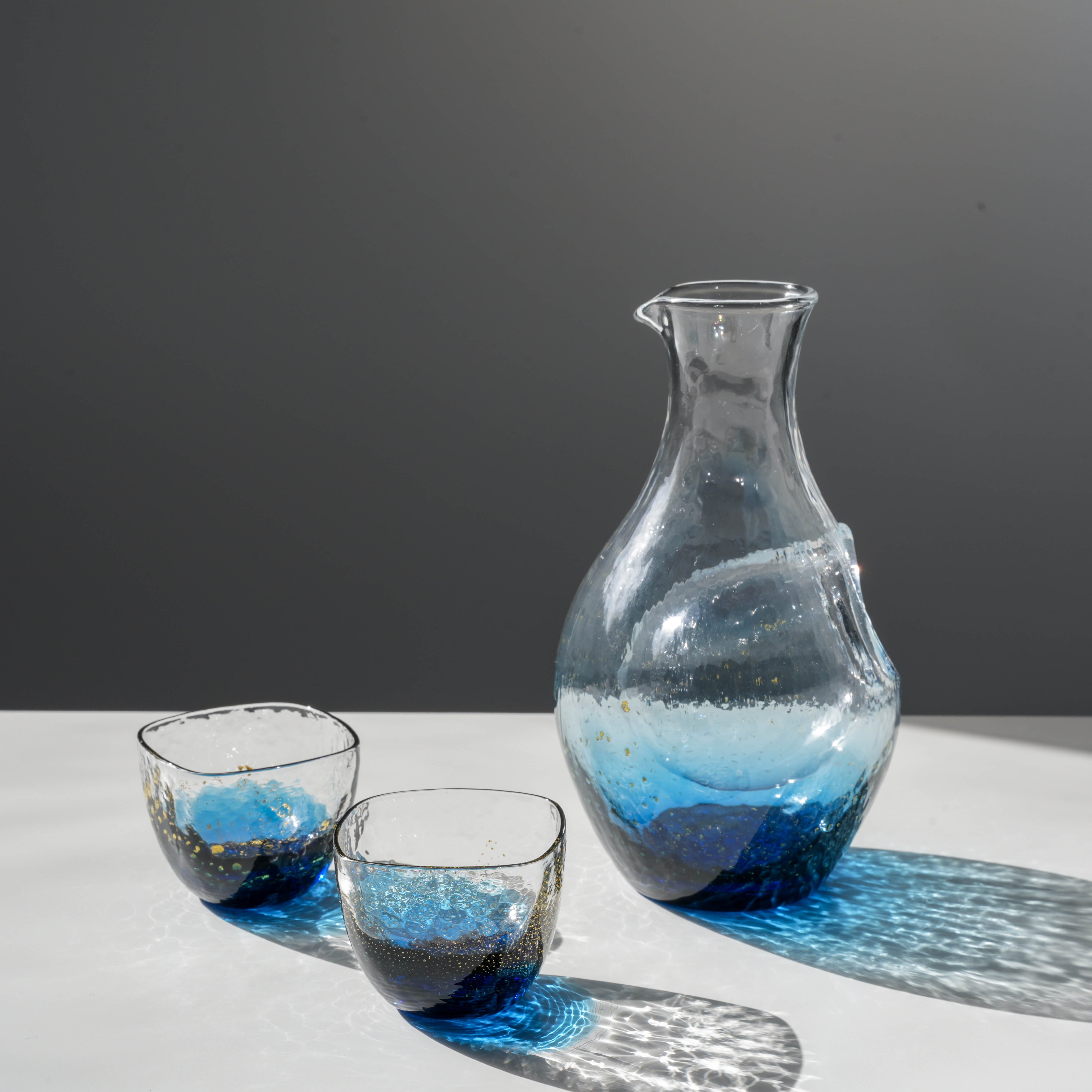 Toyo-Sasaki Sake Set - Sapphire Blue Gift features a handcrafted carafe and two glasses with gold flecks, ideal for chilled sake enjoyment.
