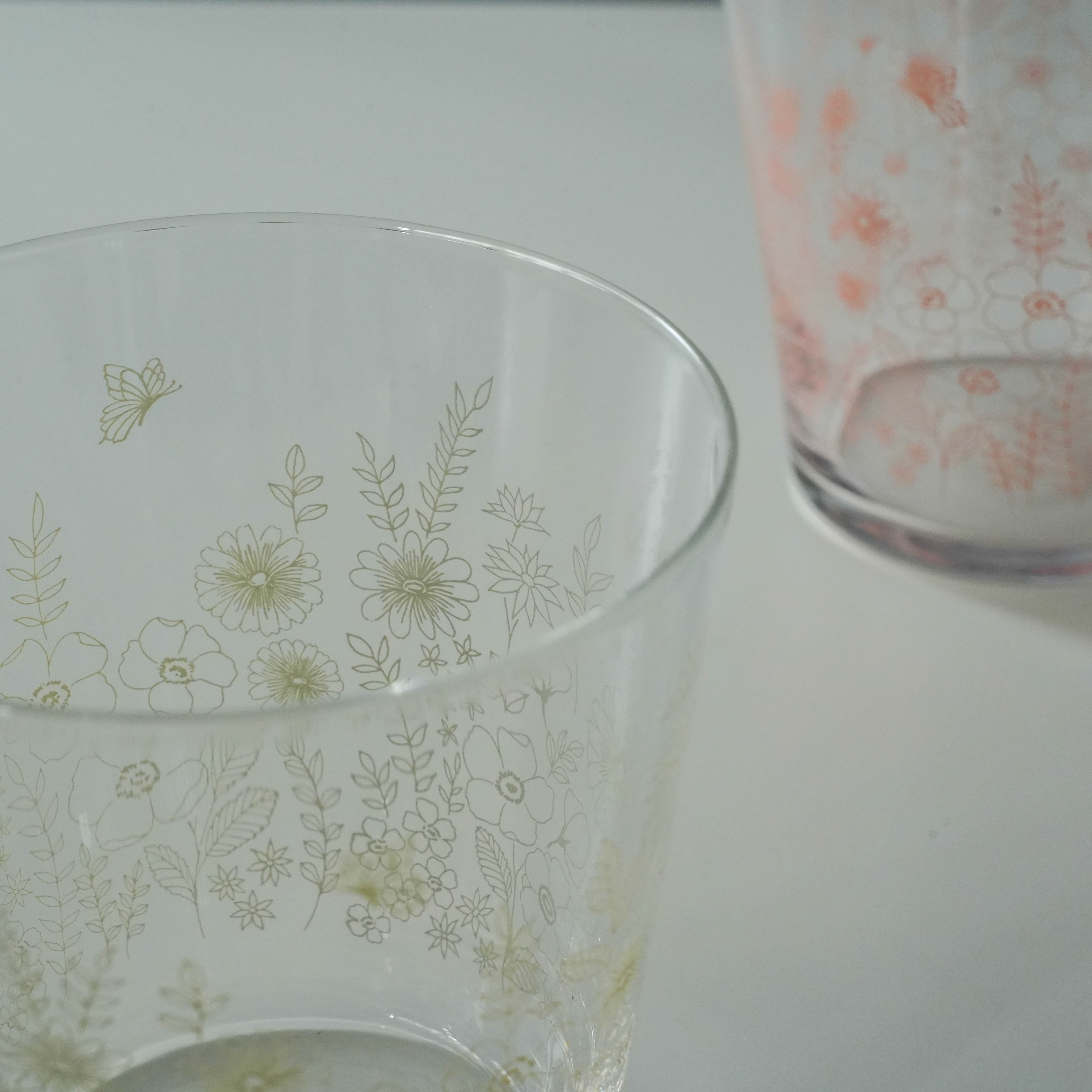 Close-up of Toyo-Sasaki Garden Time Tumblers showing intricate floral and butterfly patterns in gray and pink hues.