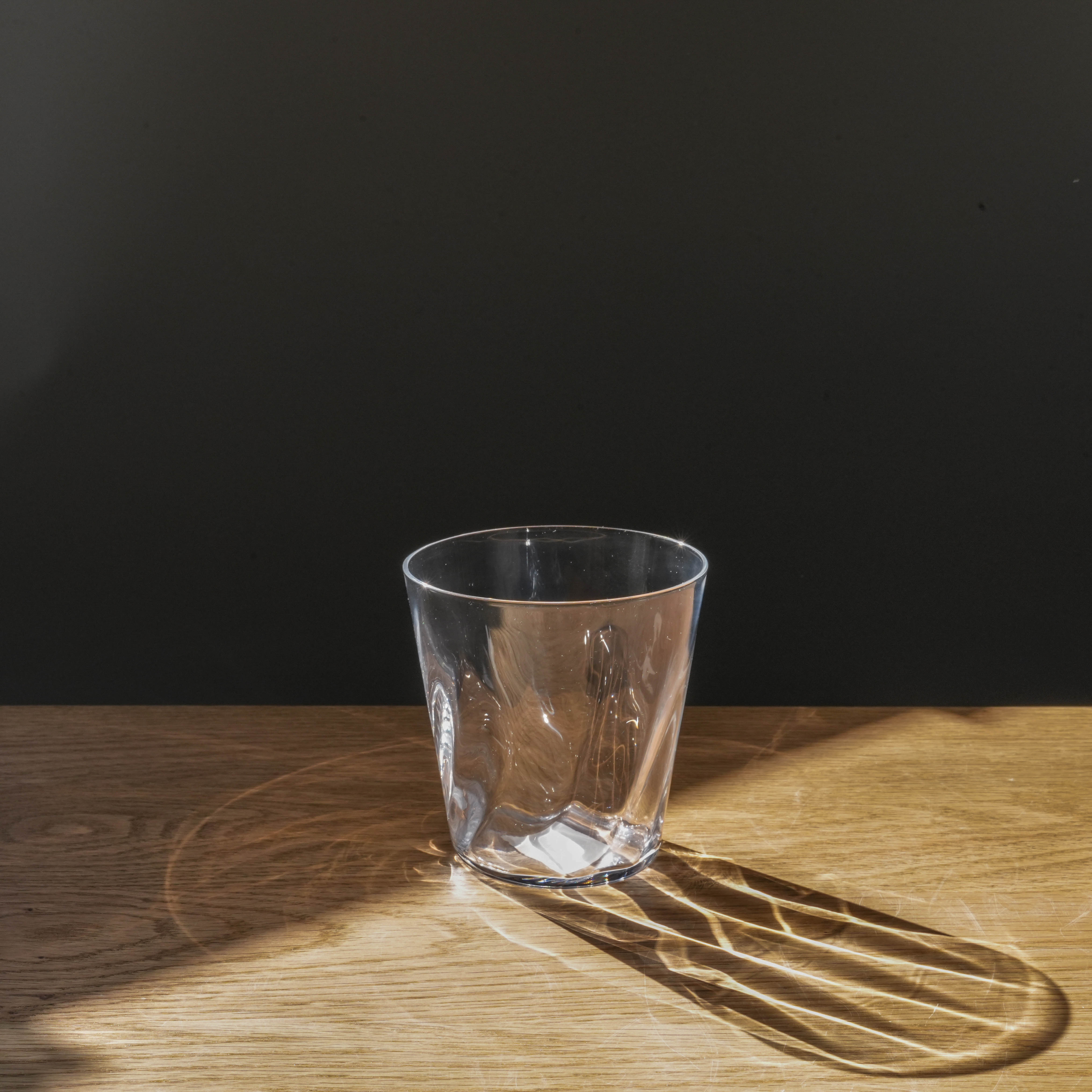 Toyo-Sasaki Sunfare Tumbler Set - Fine Clear Glass tumbler on wooden surface with elegant light reflection, ideal for stylish drinkware collections.
