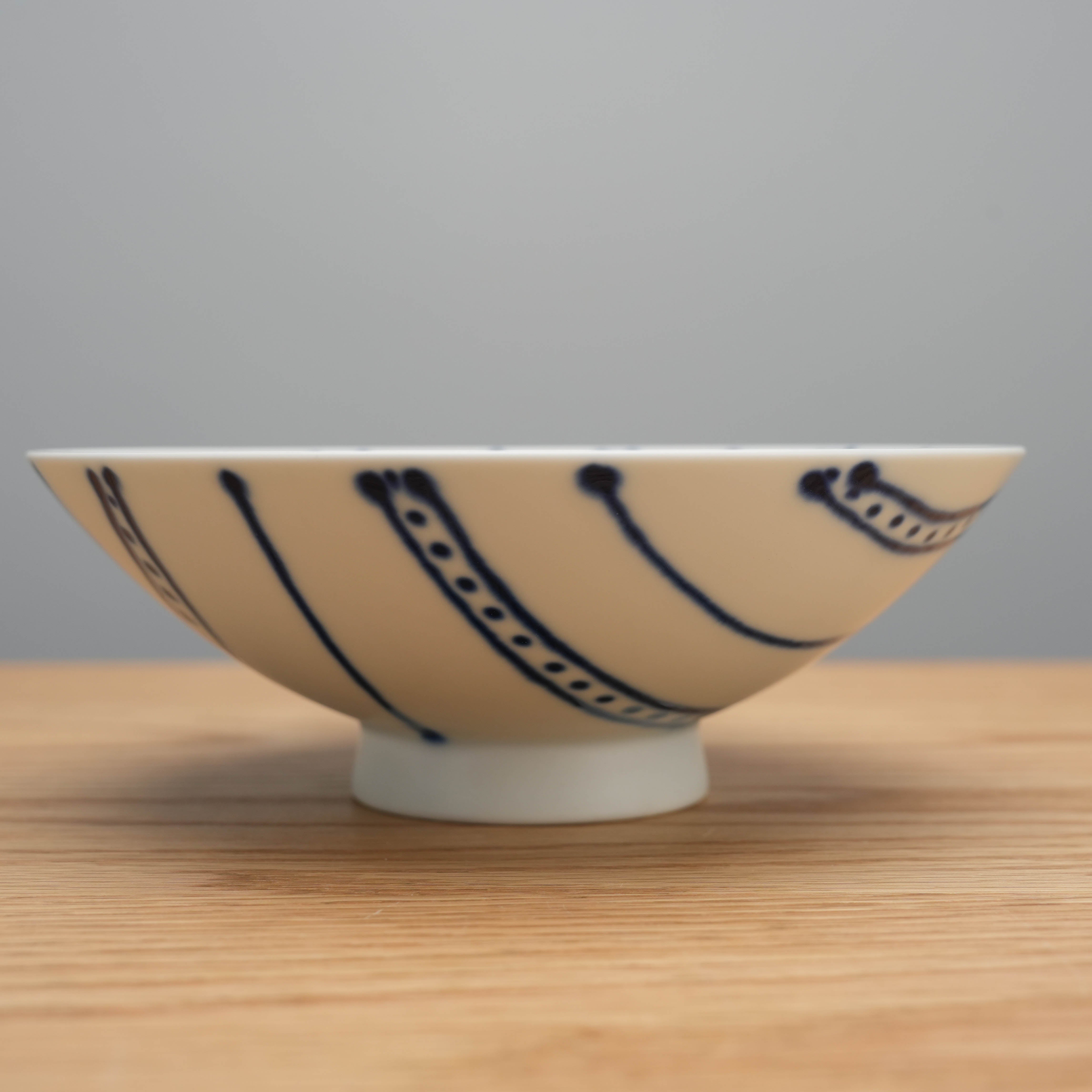 Side view of Hasami Ware Flat Bowl Blue showing curved blue stripe design, award-winning ceramic bowl for serve rice.