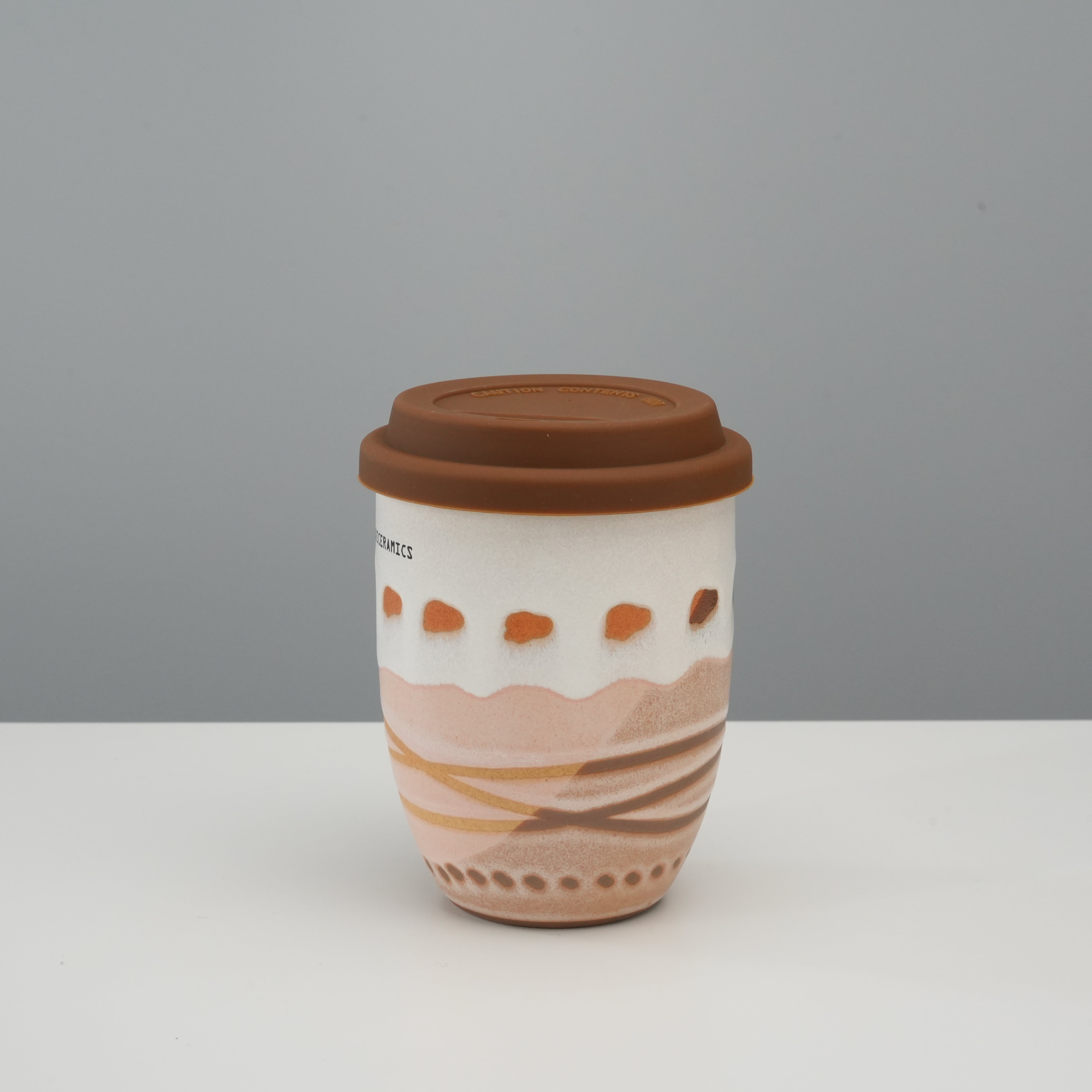 Tall Handiceramics Travel Cup - Ceramic Coffee Cup with Lid | Acorn Taro with brown silicone lid and wave-patterned terracotta base for stylish sipping.