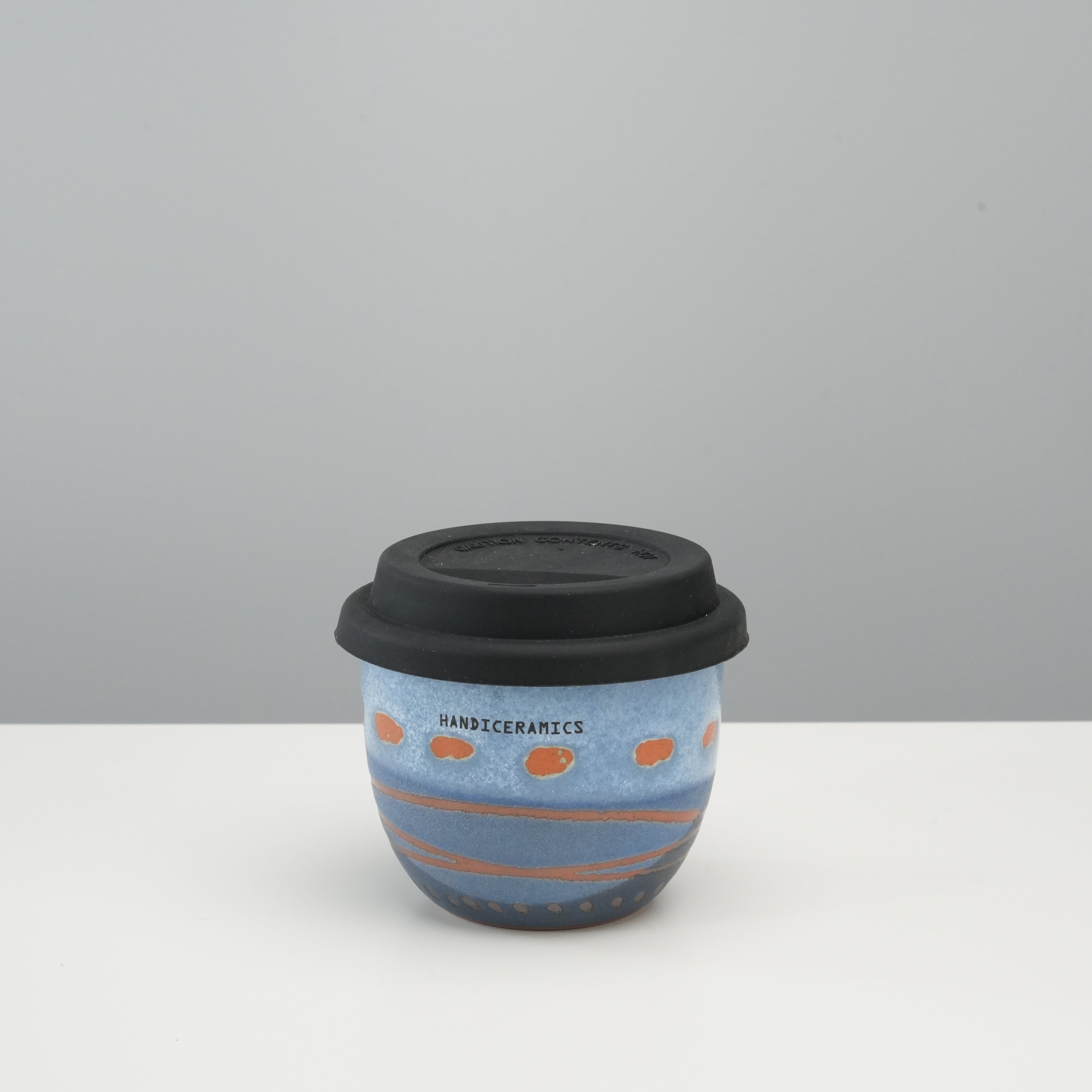Handiceramics Travel Cup - Ceramic Coffee Cup with Lid in Marine blue with orange accents, featuring a black silicone lid, ideal for on-the-go use.
