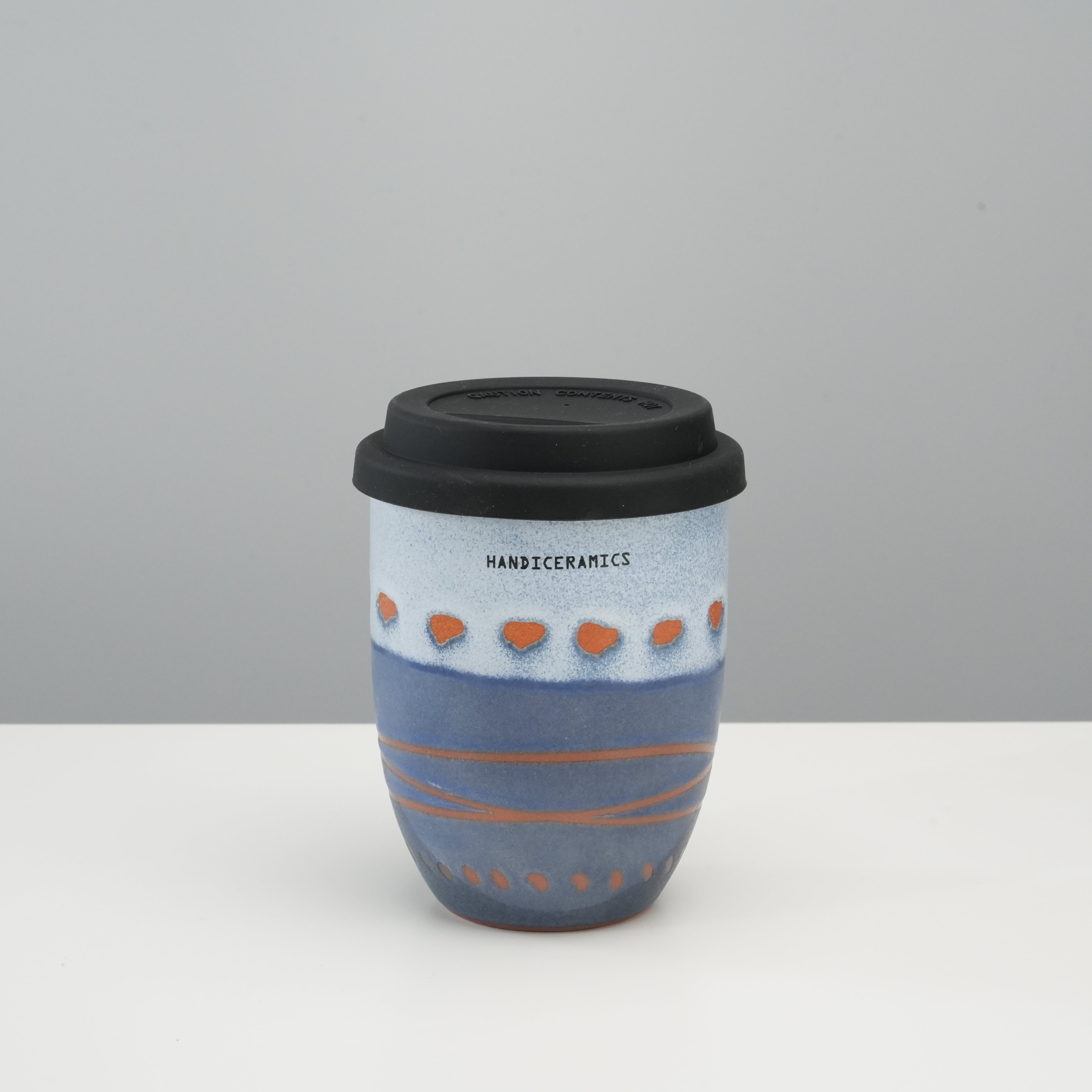 Tall version of Handiceramics Travel Cup - Ceramic Coffee Cup with Lid in Marine, featuring hand-painted orange dots and black silicone lid.