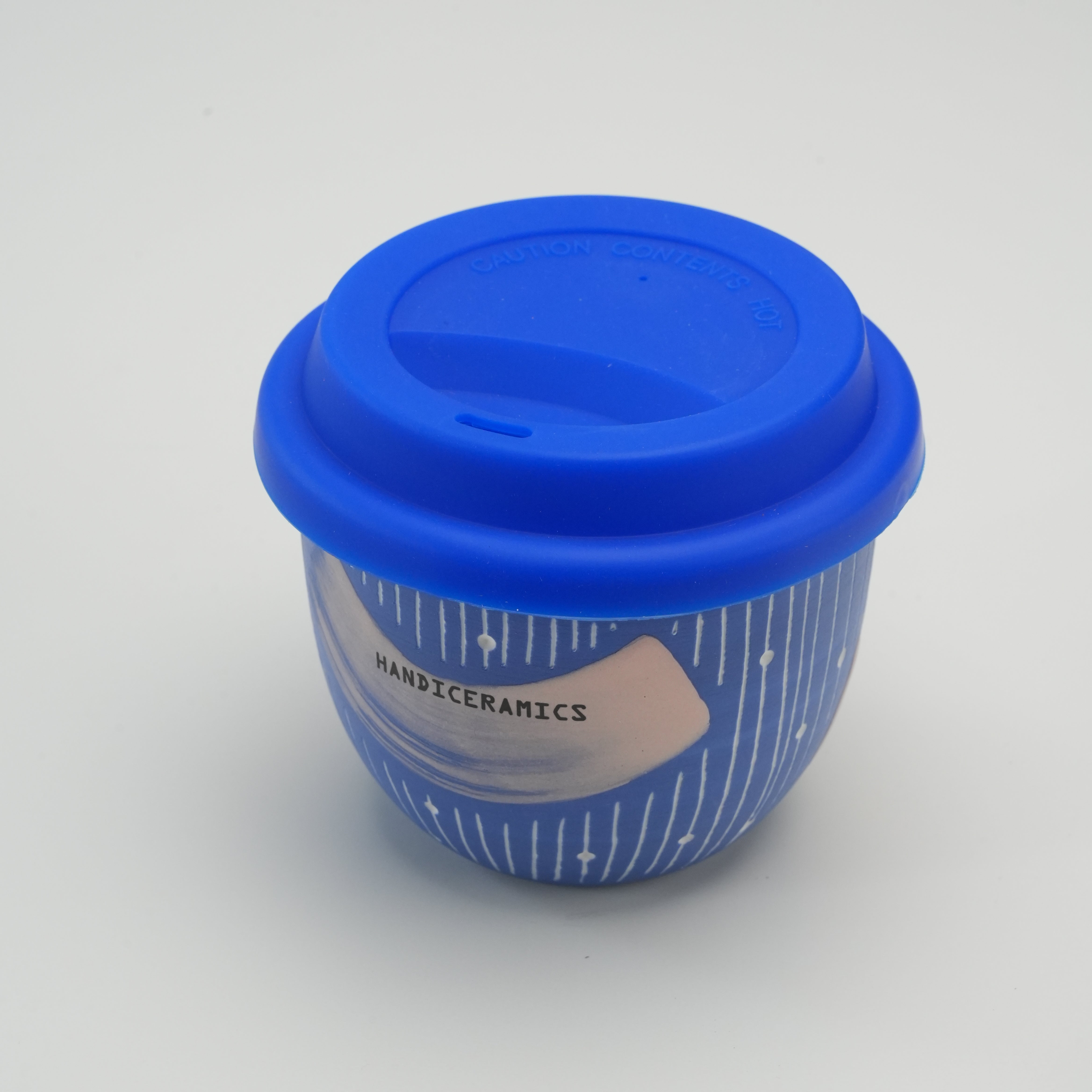 Blueberry Handiceramics Macarons Travel Cup with secure blue silicone lid, ideal for coffee or tea, part of ceramic drinkware collection.