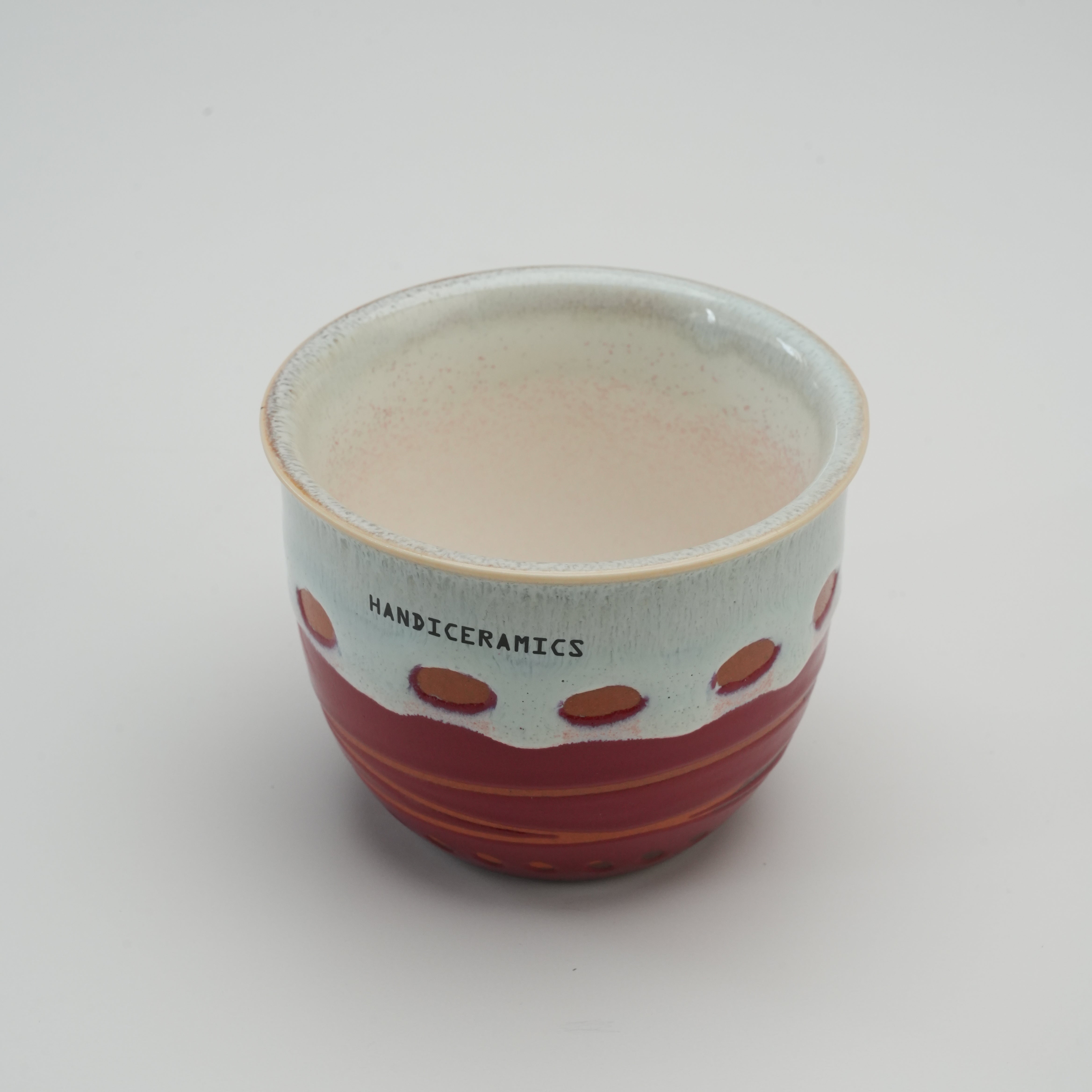 Interior view of the Handiceramics Travel Cup without lid, revealing the smooth ceramic finish and artisan raspberry glaze ideal for hot beverages.