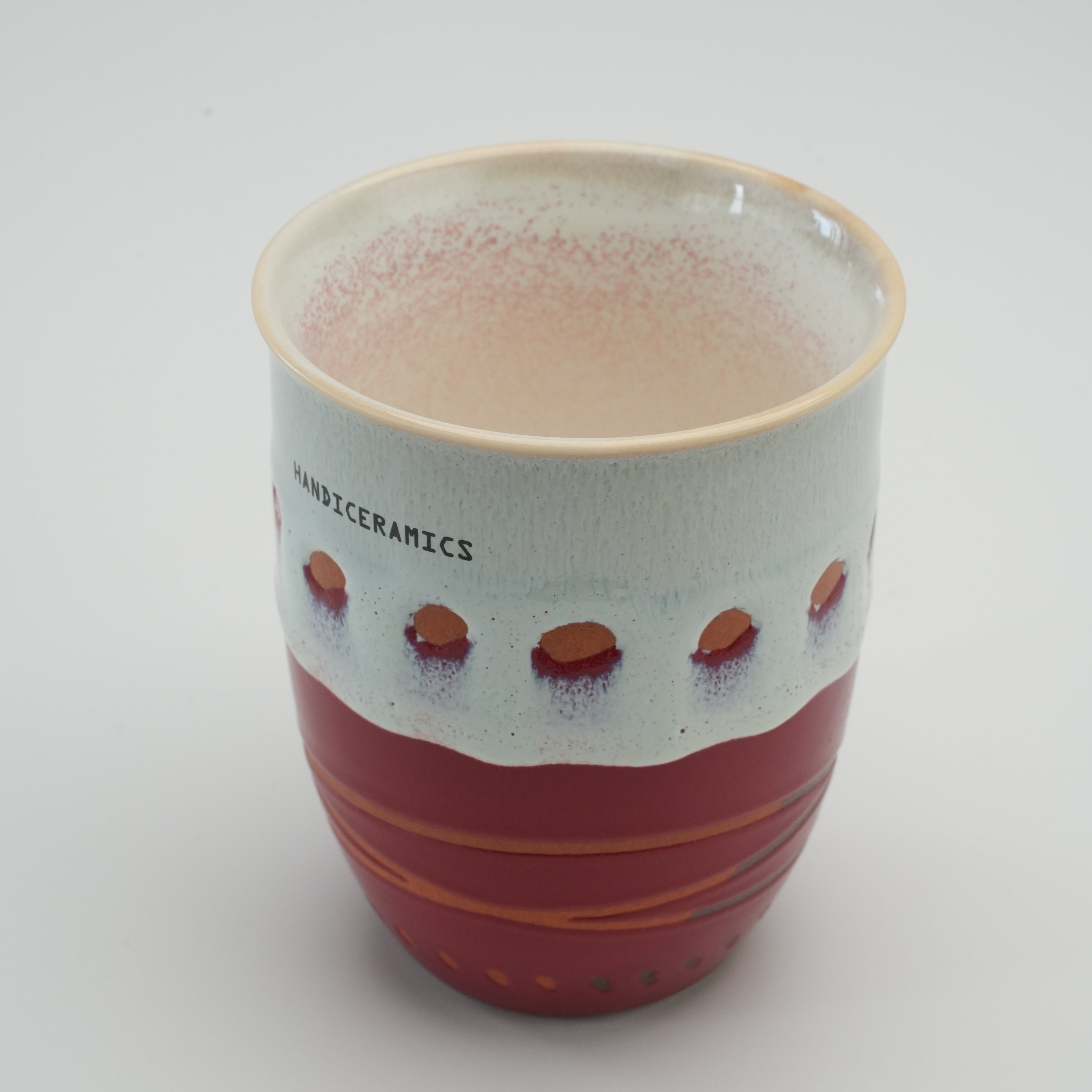Open Handiceramics Acorn Travel Cup in raspberry, showing the glazed ceramic interior and artistic exterior design perfect for eco-friendly coffee lovers.