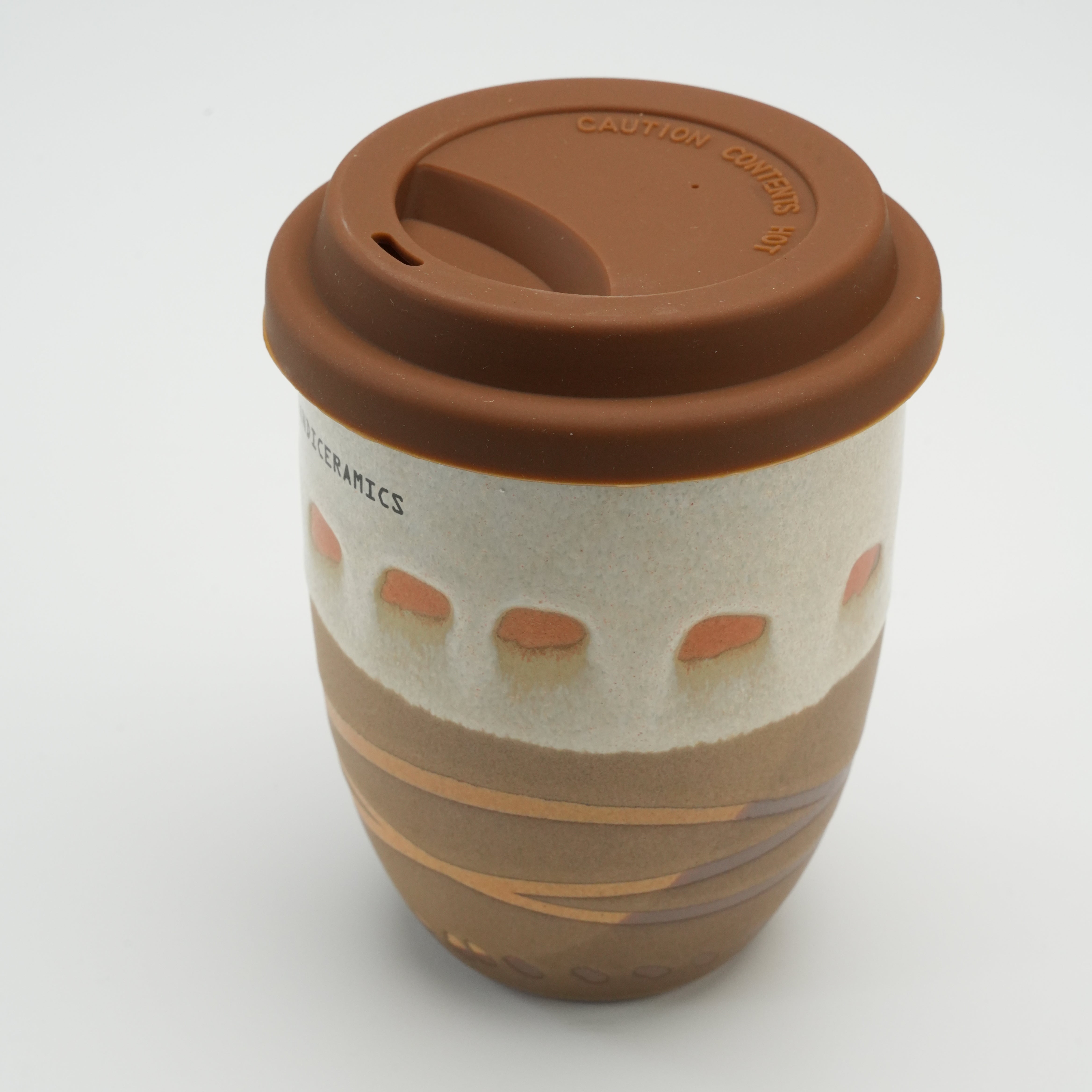 Close-up of mocha Handiceramics Travel Cup with silicone lid, highlighting textured ceramic body and modern artisan design.