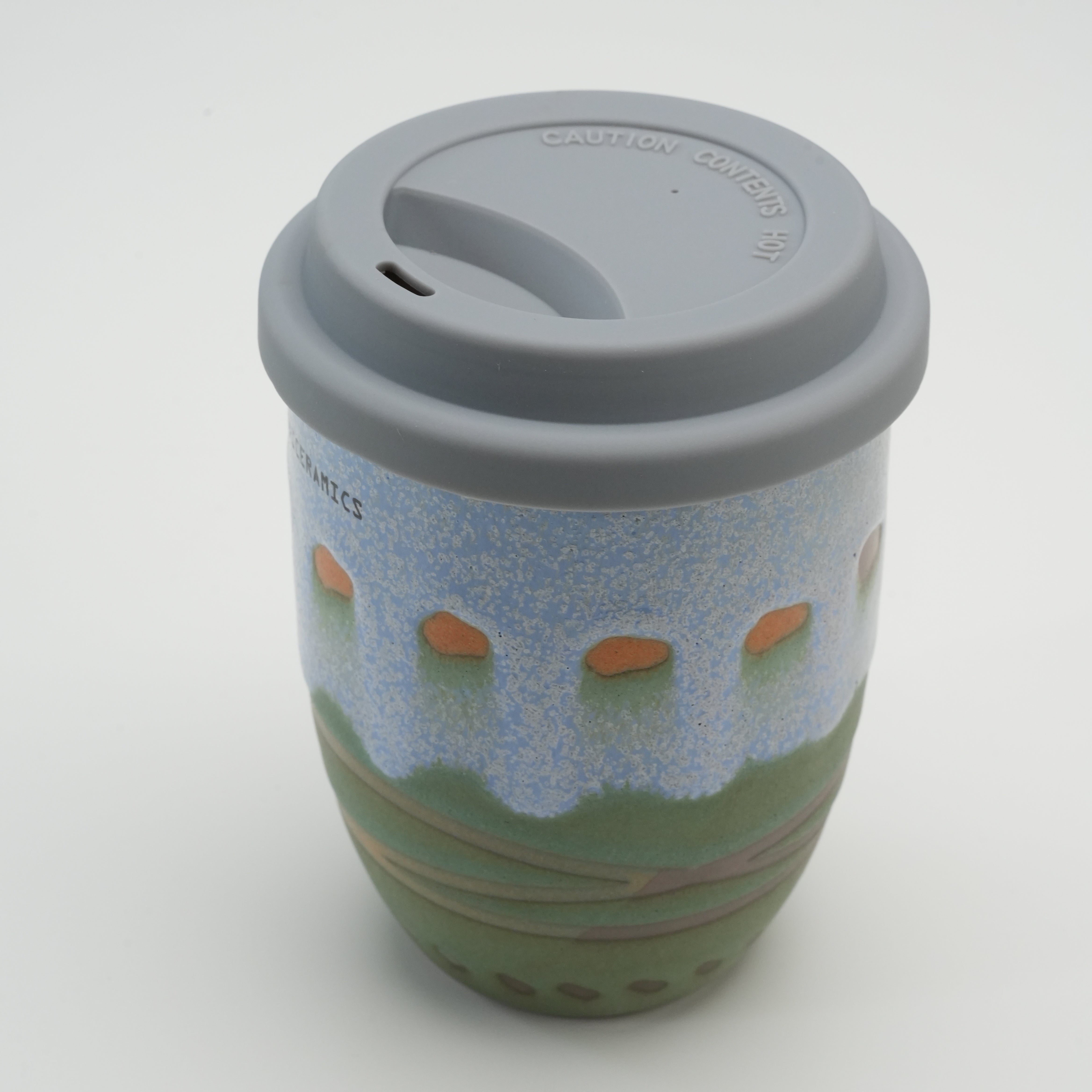 Close-up of the Handiceramics Palm Beach ceramic travel cup with lid, emphasizing the textured glaze and ergonomic drinking spout.