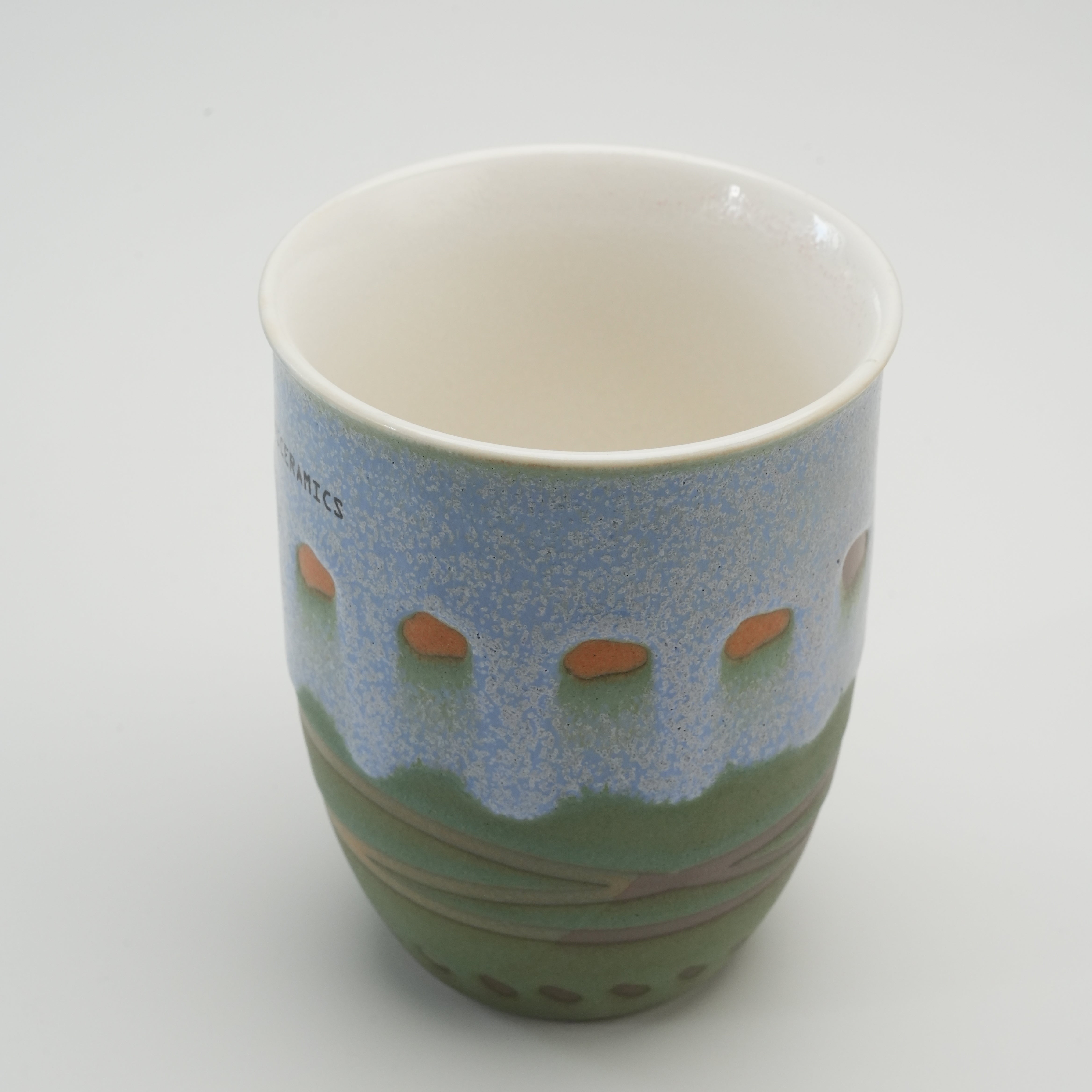 Open view of the Handiceramics Travel Cup - Ceramic Coffee Cup with Lid | Palm Beach, showing the spacious interior and artistic exterior detailing.