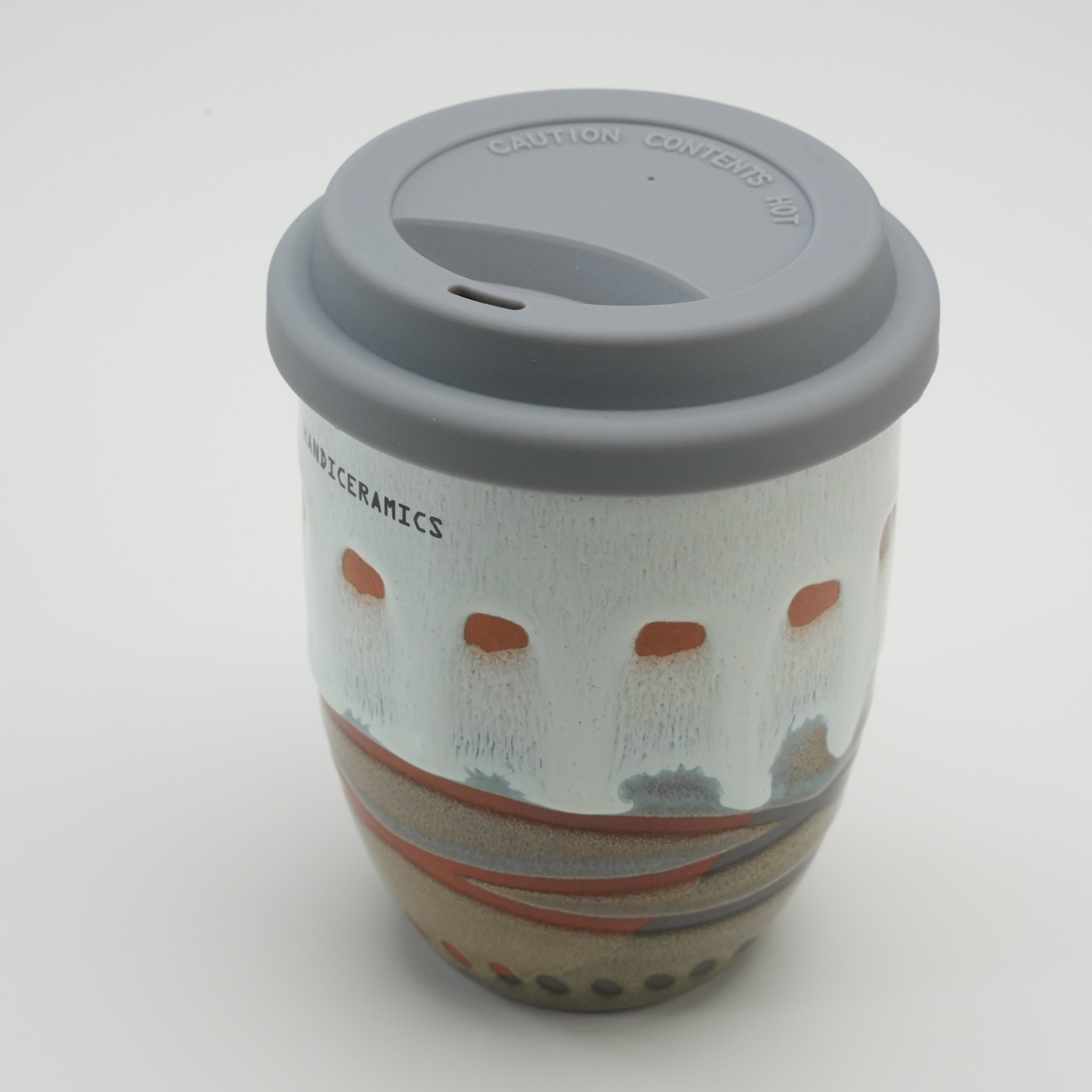 Angled top view of Handiceramics Travel Cup - Ceramic Coffee Cup with Lid, showcasing silicone lid and unique handmade ceramic texture.