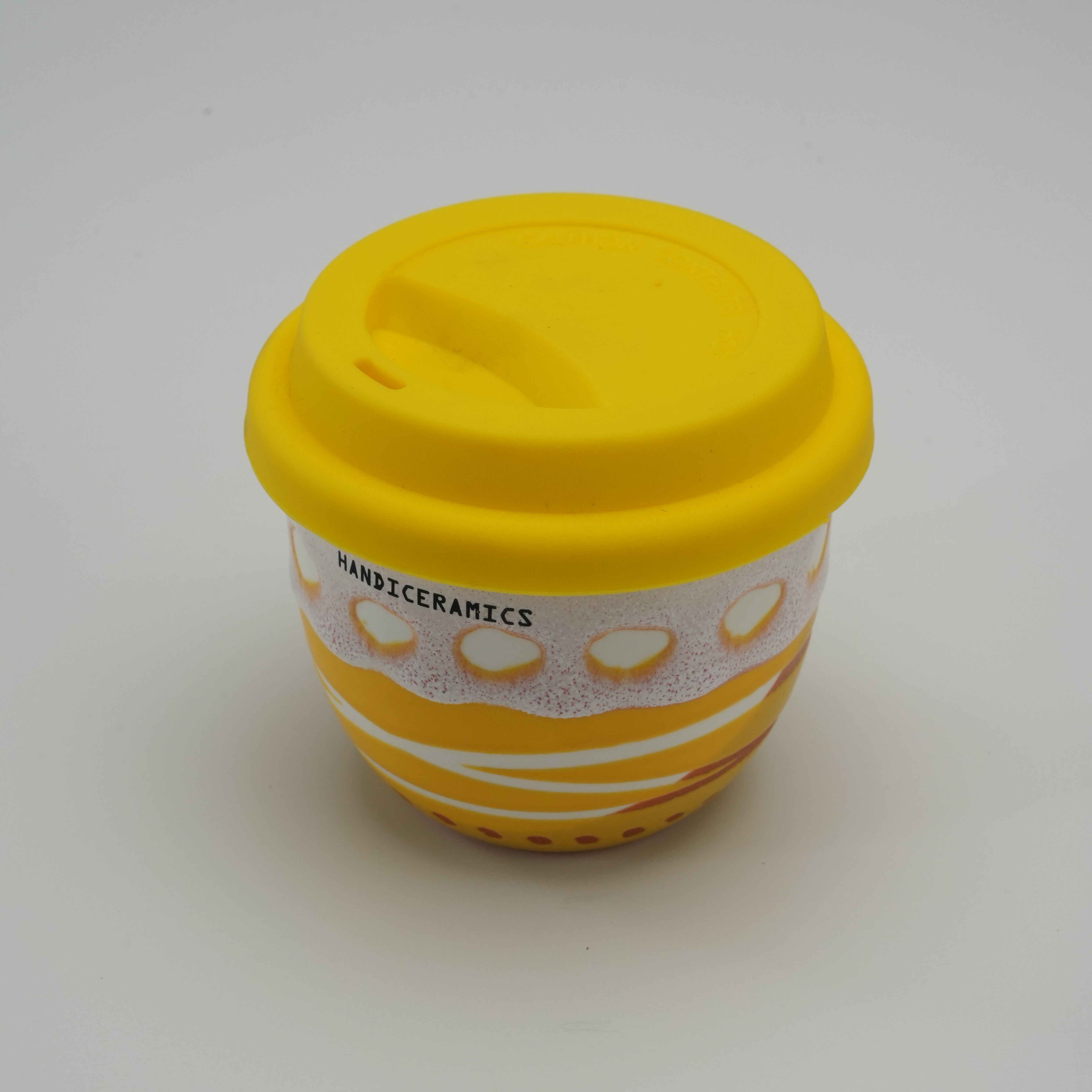Top view of Handiceramics Acorn Lemon Cup with yellow silicone lid, showcasing the ceramic texture and artistic design for stylish sipping.
