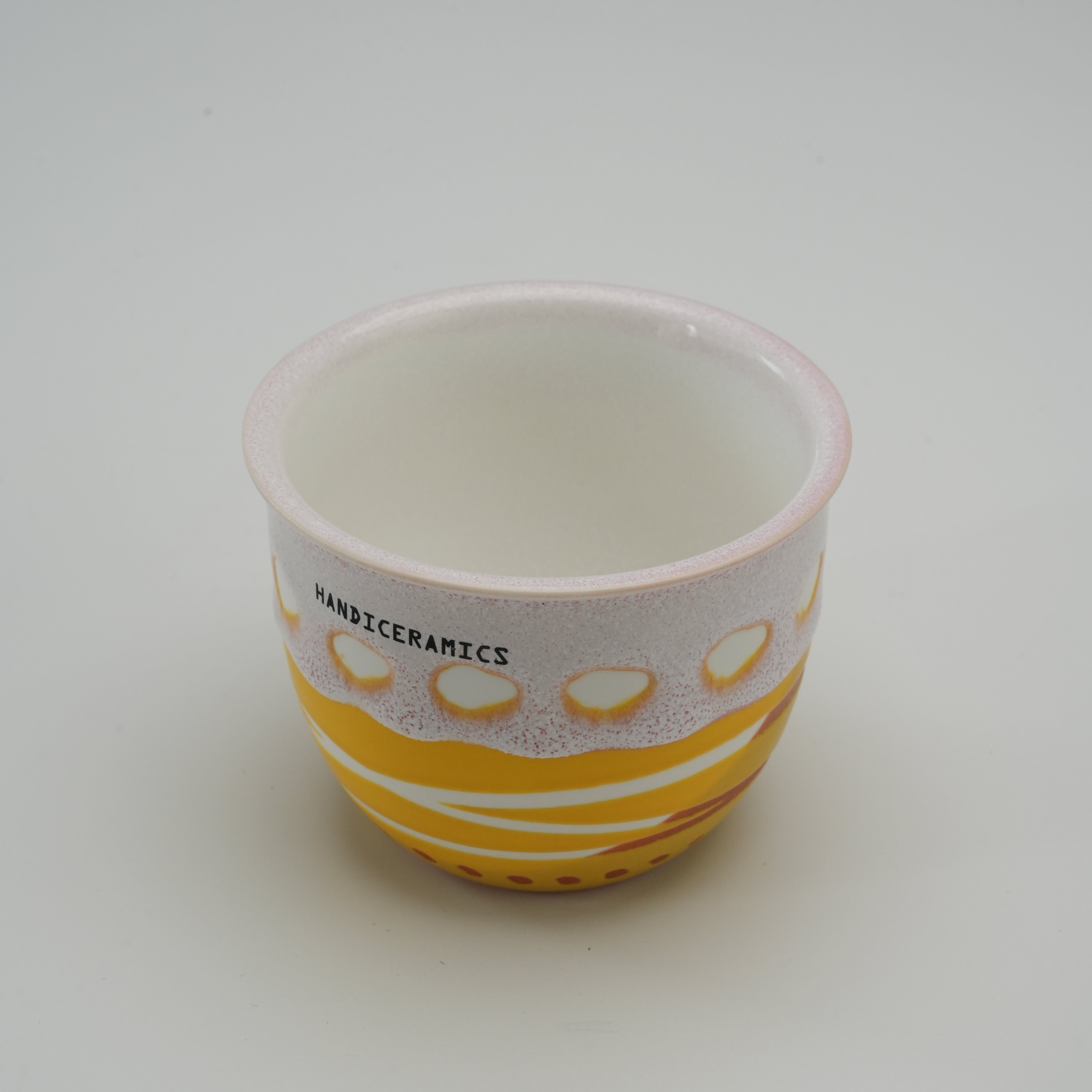 Open Handiceramics Acorn Travel Cup in Lemon, highlighting the smooth ceramic interior and hand-painted exterior pattern without the lid.