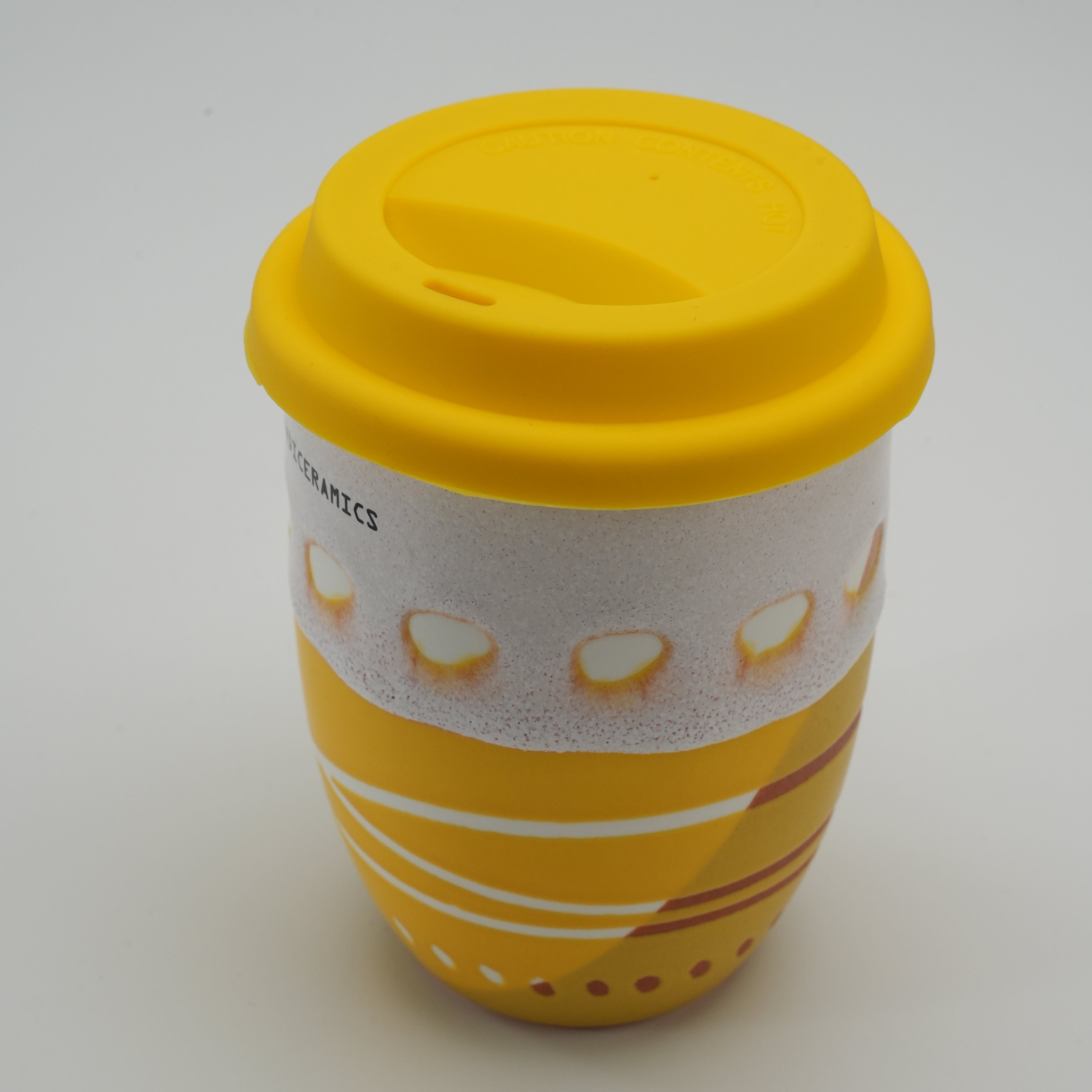 Angled view of Handiceramics Acorn Lemon Cup with lid, showing detailed ceramic craftsmanship and ergonomic silicone lid for travel use.