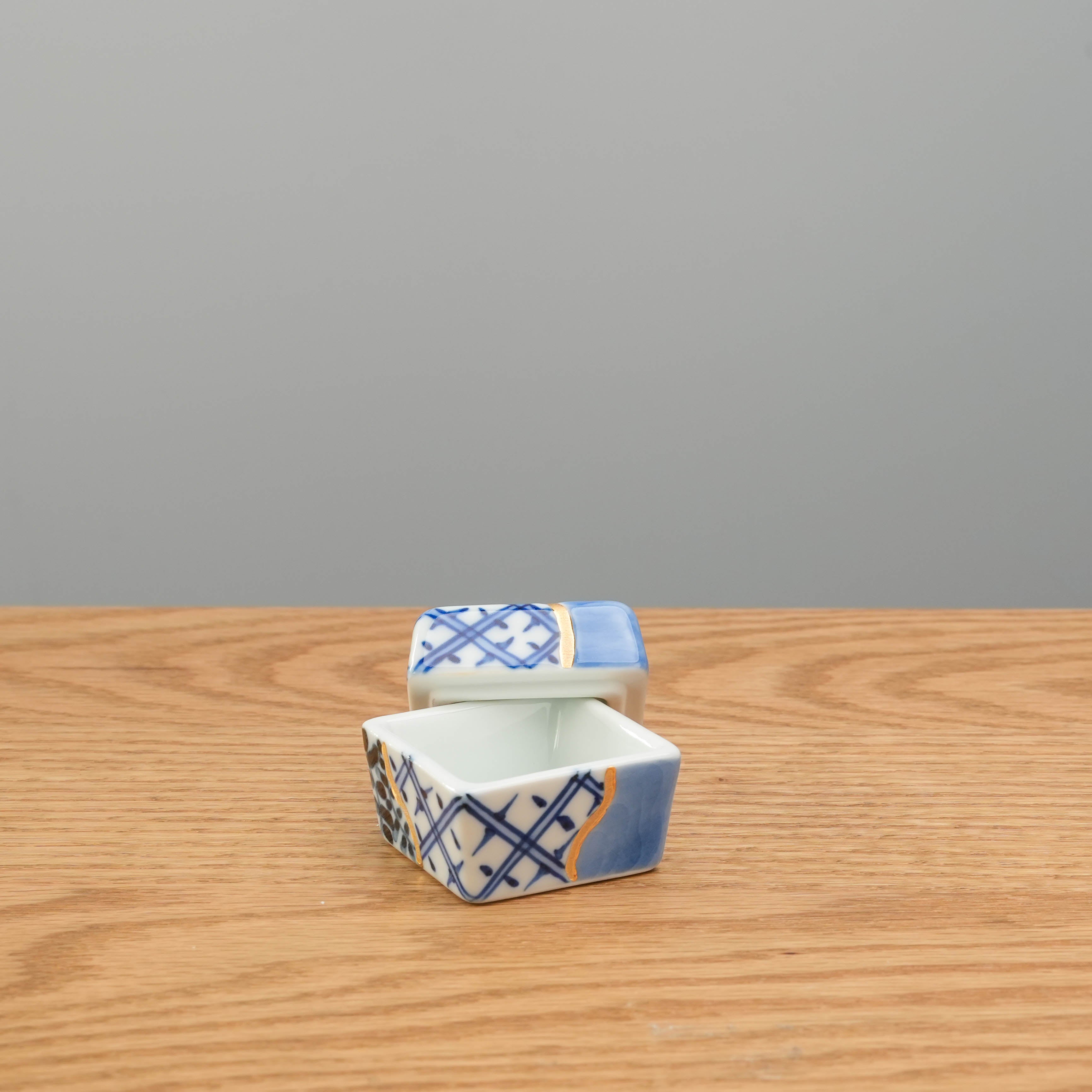 Partially open Arita kintsugi-style Delicacy Container with visible interior and detailed exterior design. Ideal for condiments or table presentation.