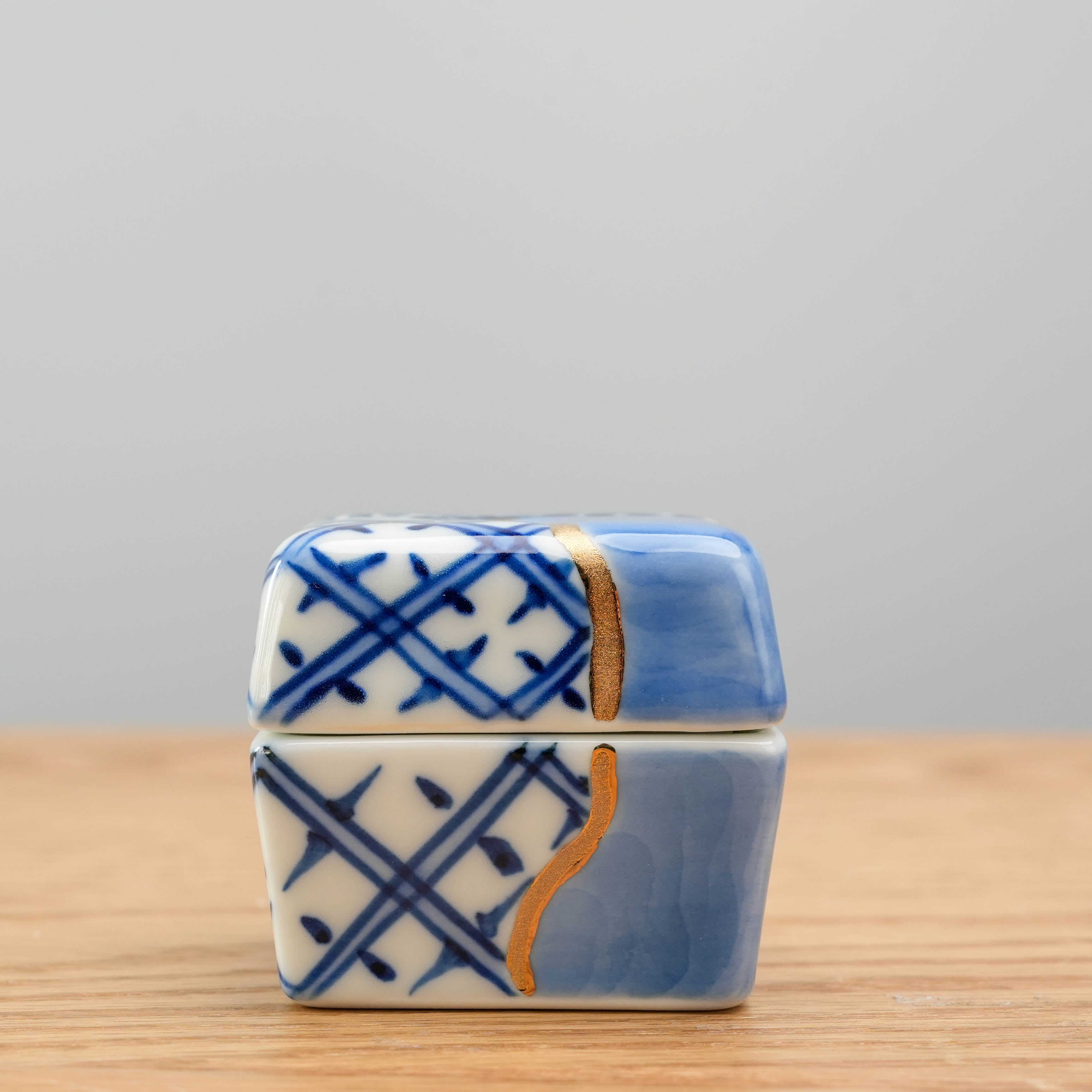 Front view of Arita kintsugi-style Delicacy Container with symmetrical blue and white patterns and gold repair lines. Stylish condiment holder.