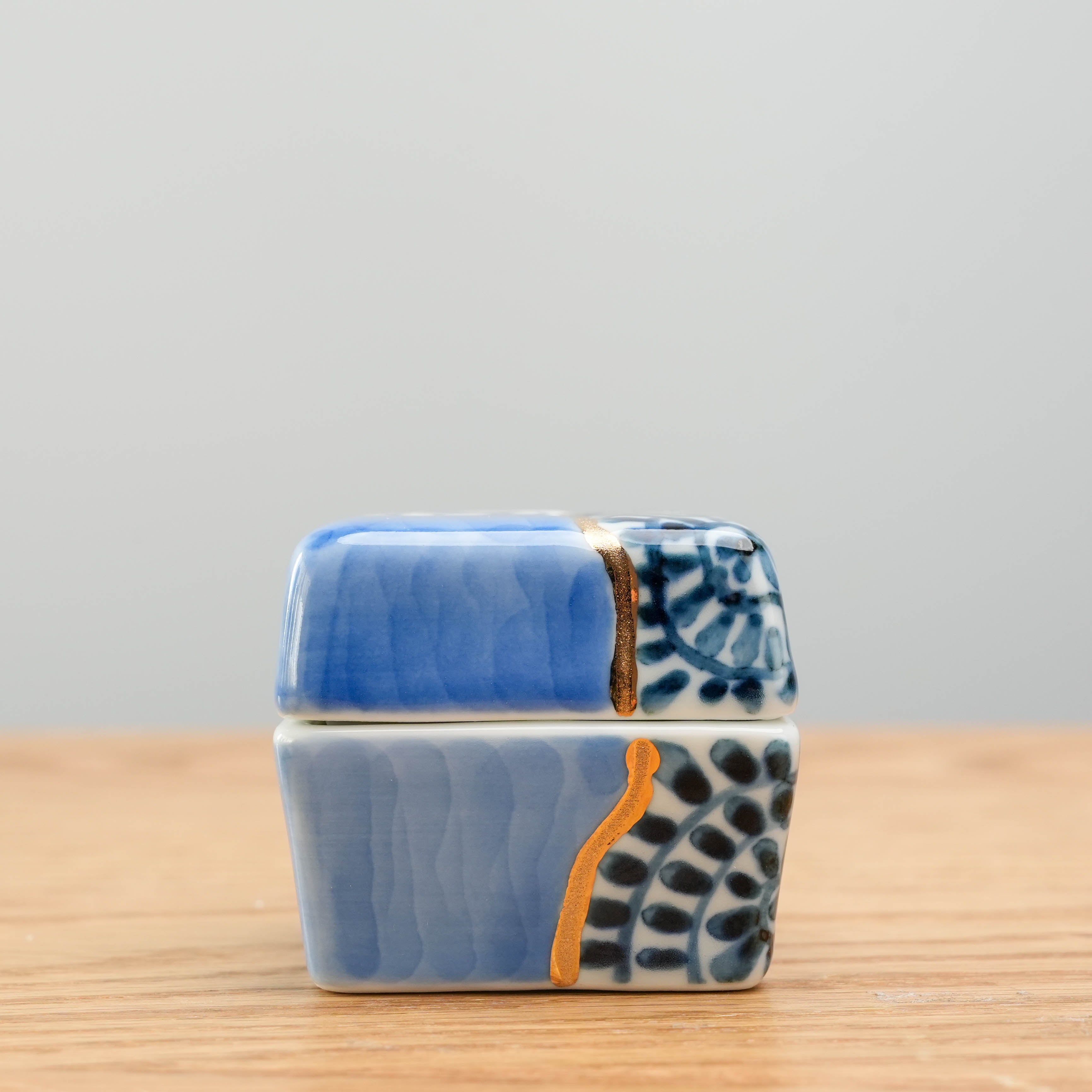 Side view of Arita kintsugi-style Delicacy Container showcasing textured blue glaze and floral motifs. Elegant Japanese design for kitchen use.