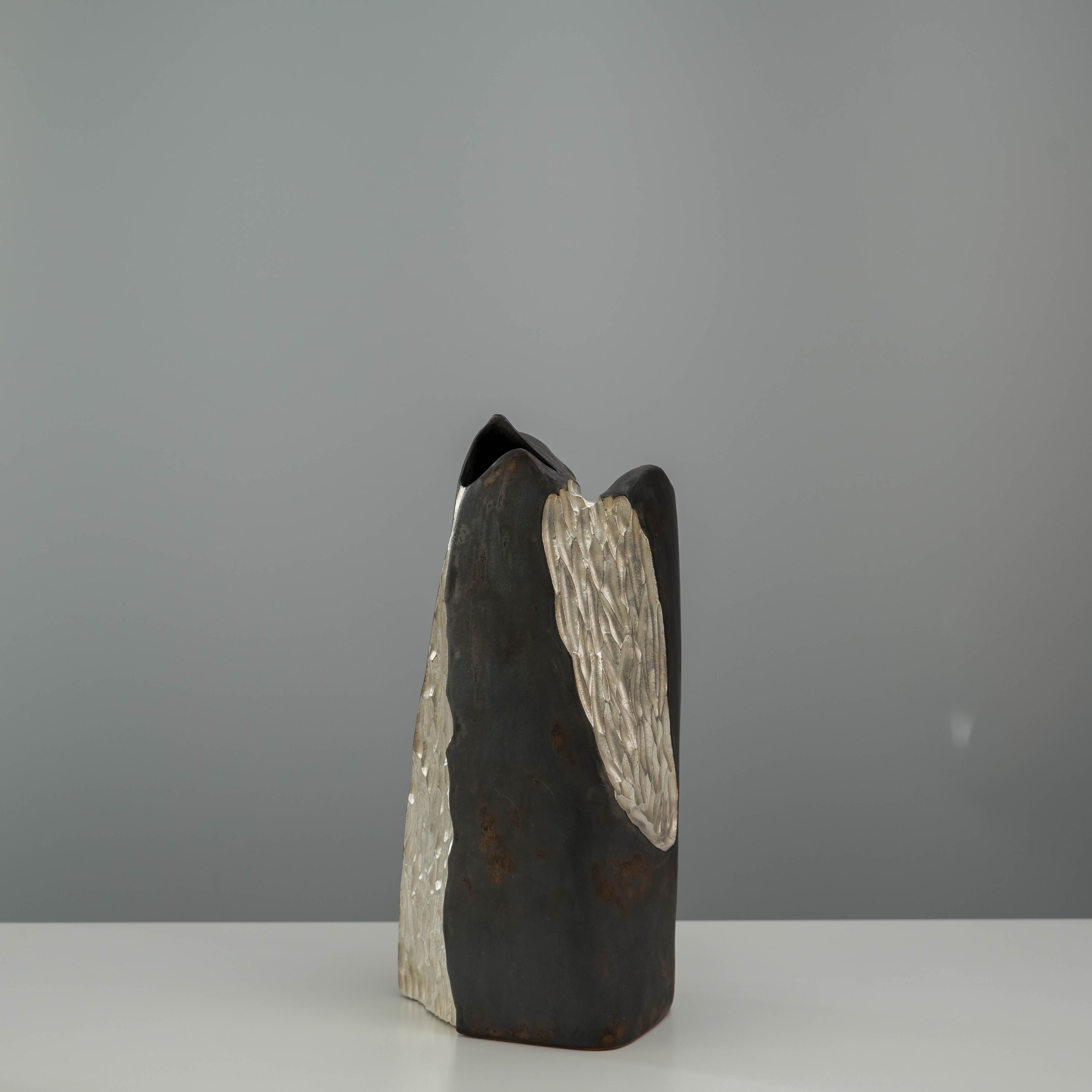 Side view of the Lonesome Studio Mountain Form Flower Vase showing textured silver detailing on a dark ceramic body.