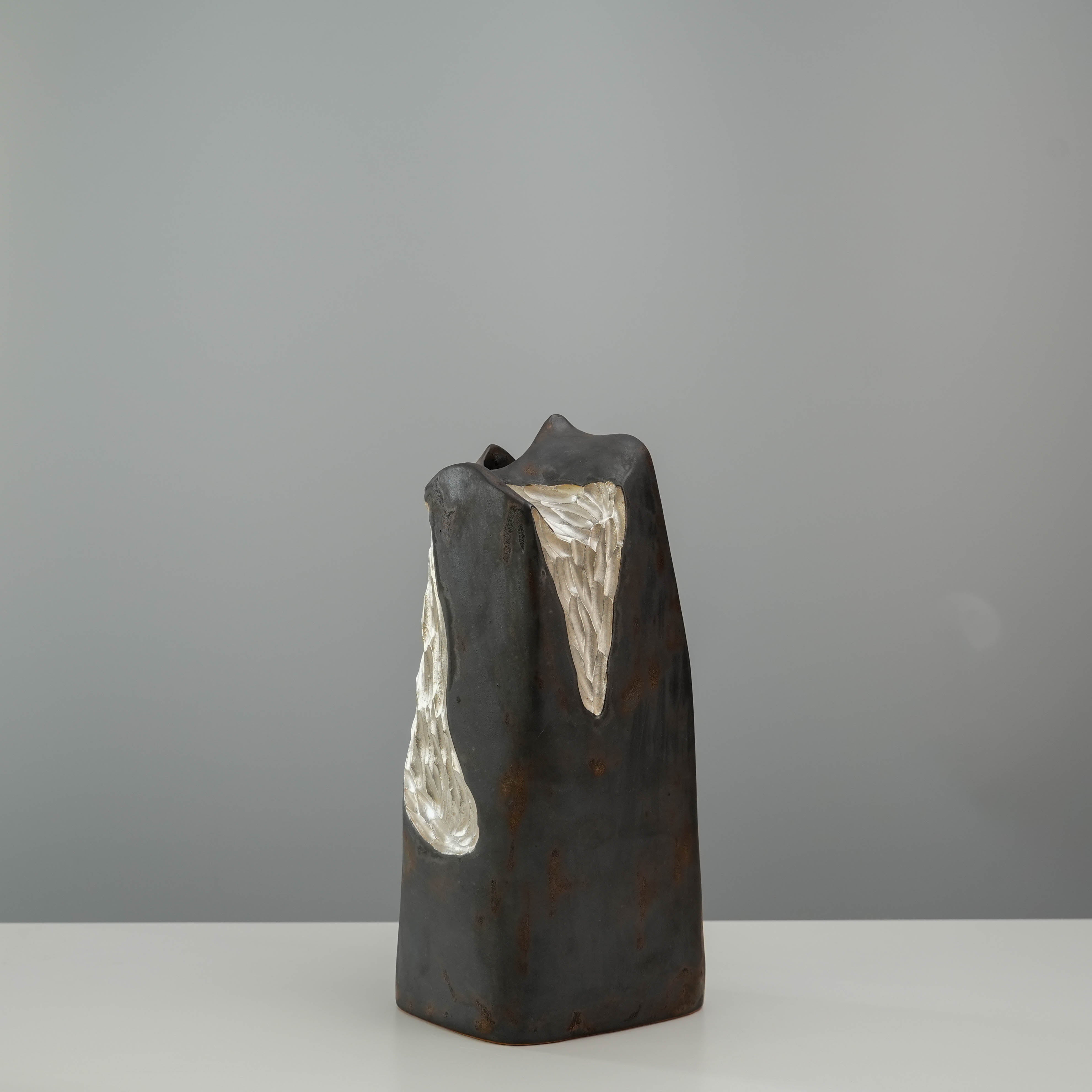 Rear angle of the Mountain Form Vase by Lonesome Studio, highlighting silver accents on a matte black-gold ceramic surface.