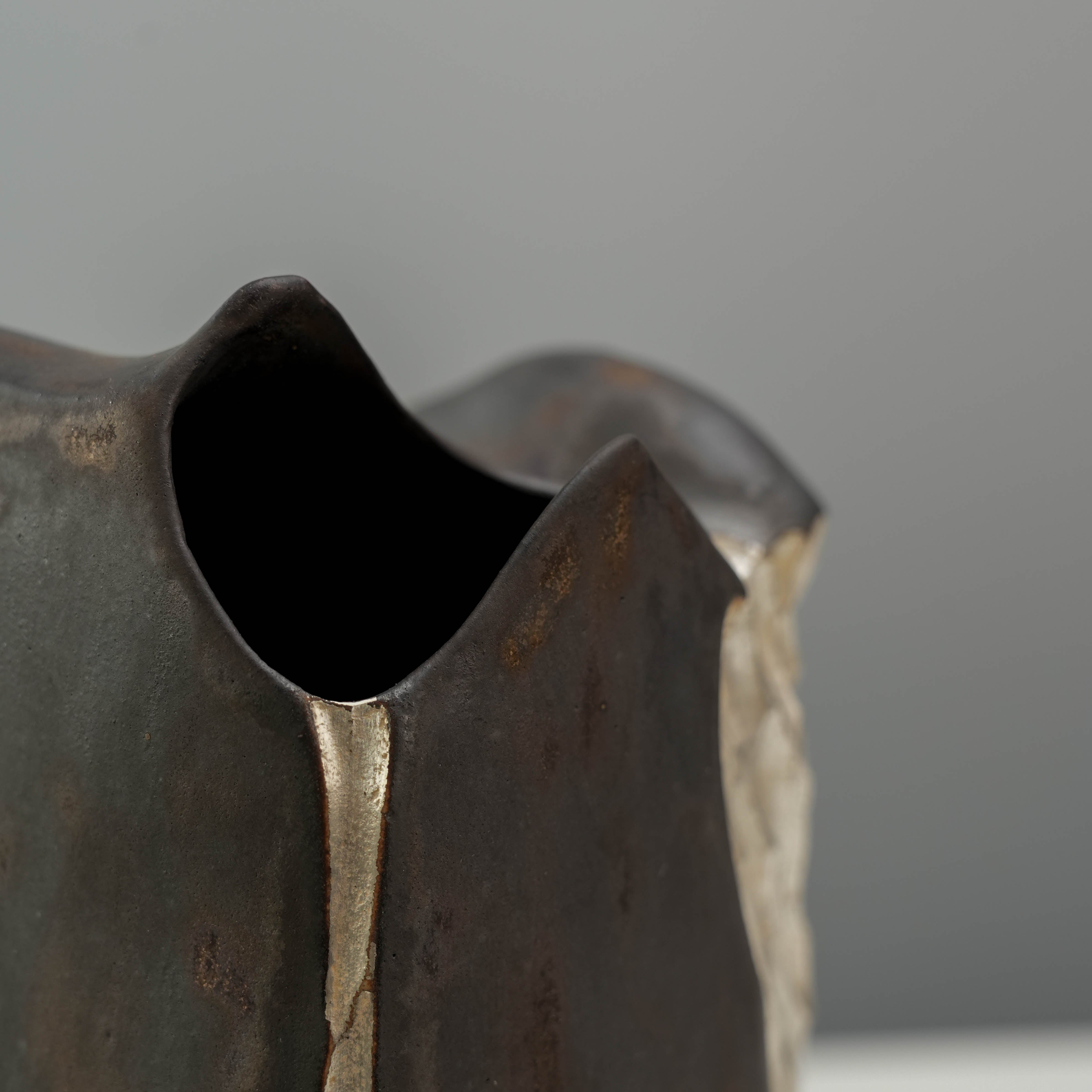Top detail of the Mountain Form Flower Vase with an organic, peak-like opening and black-gold ceramic finish.