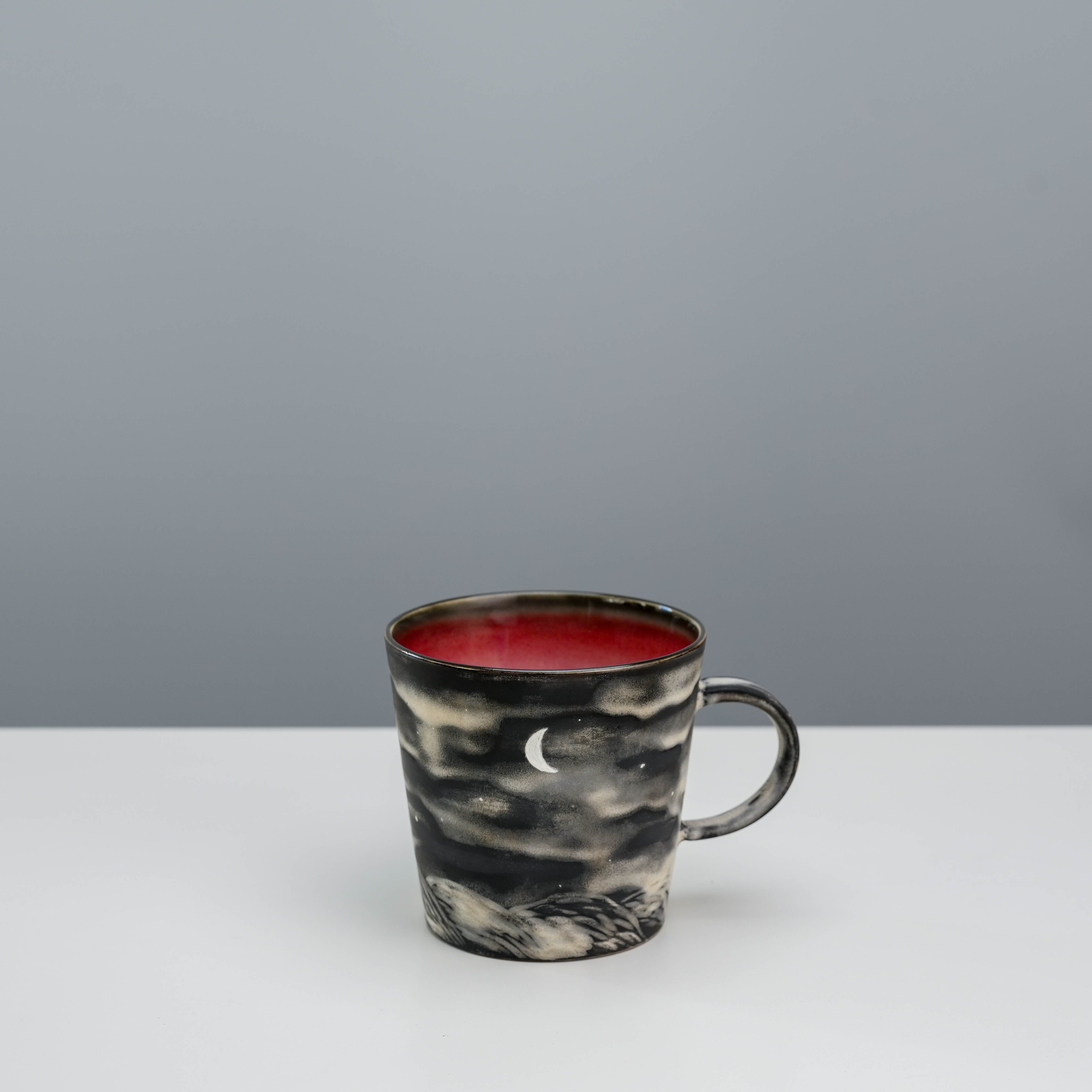 Lonesome Studio Crescent Moon coffee mug with silver glaze patterns and red interior, showcasing moonlit scenery.