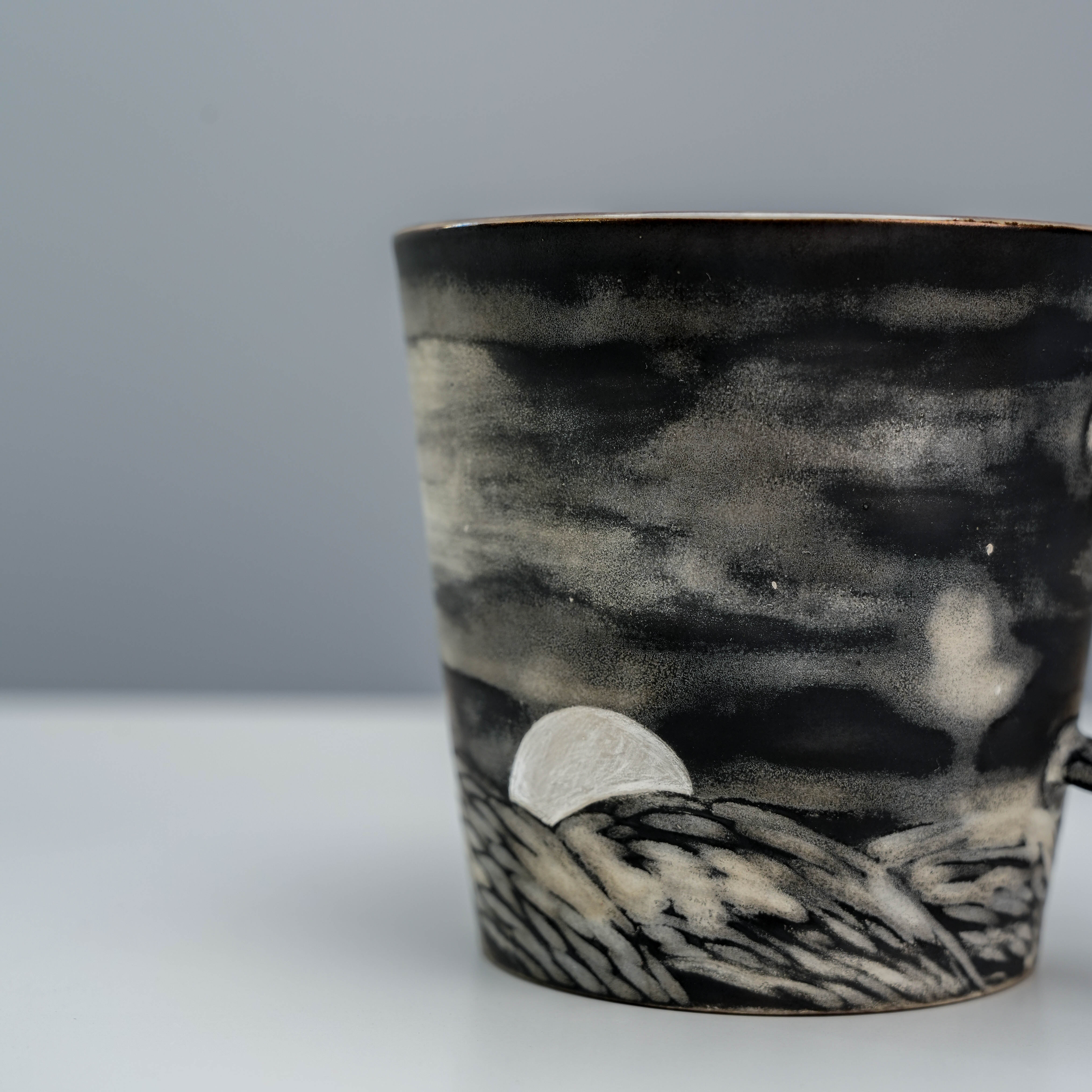 Detailed close-up of moon and hill carvings on the Evening Moon Mug, showcasing artistic ceramic craftsmanship in drinkware.
