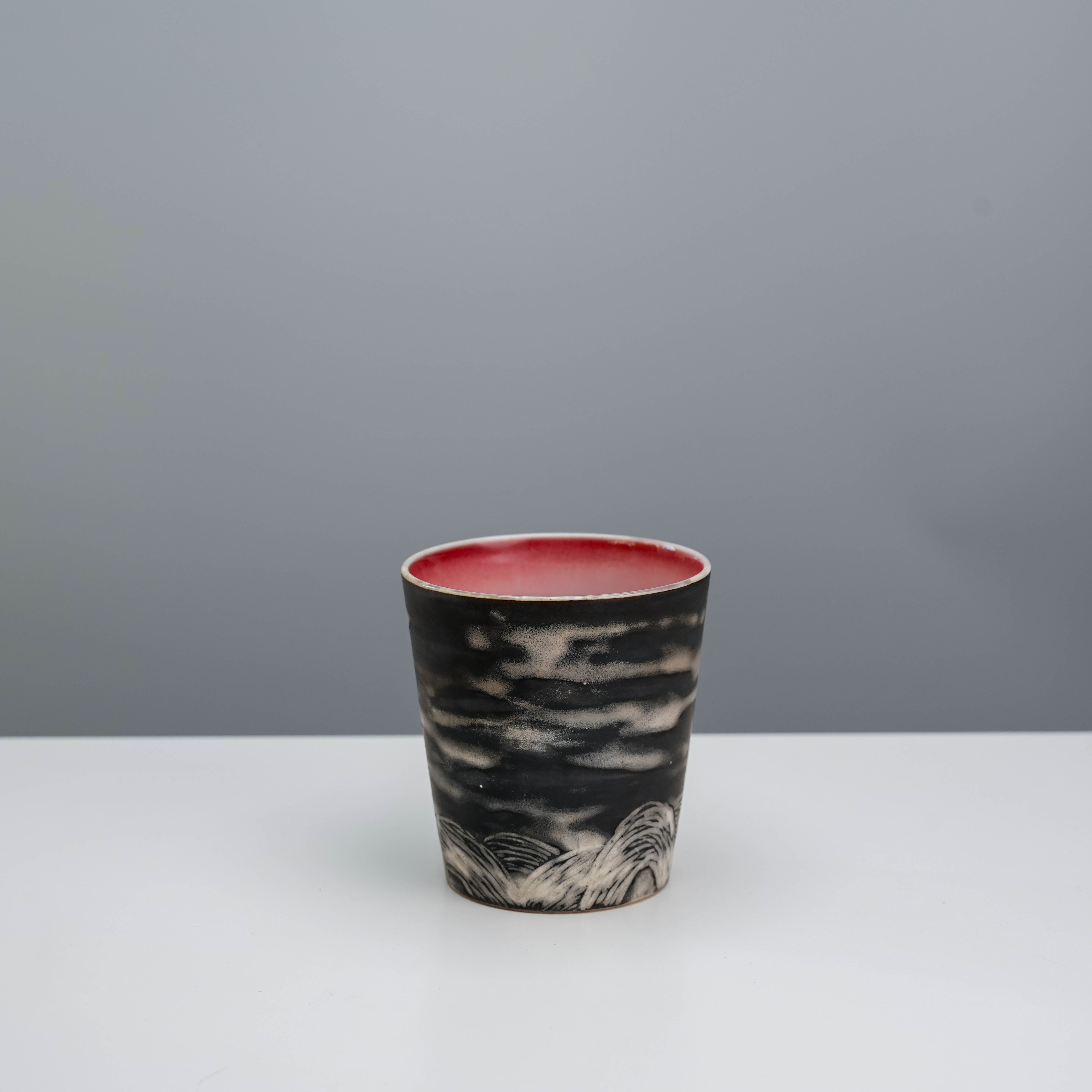 Back view of Lonesome Studio Evening Moon Tumbler showing hand-carved cloud and mountain details in black ceramic finish.