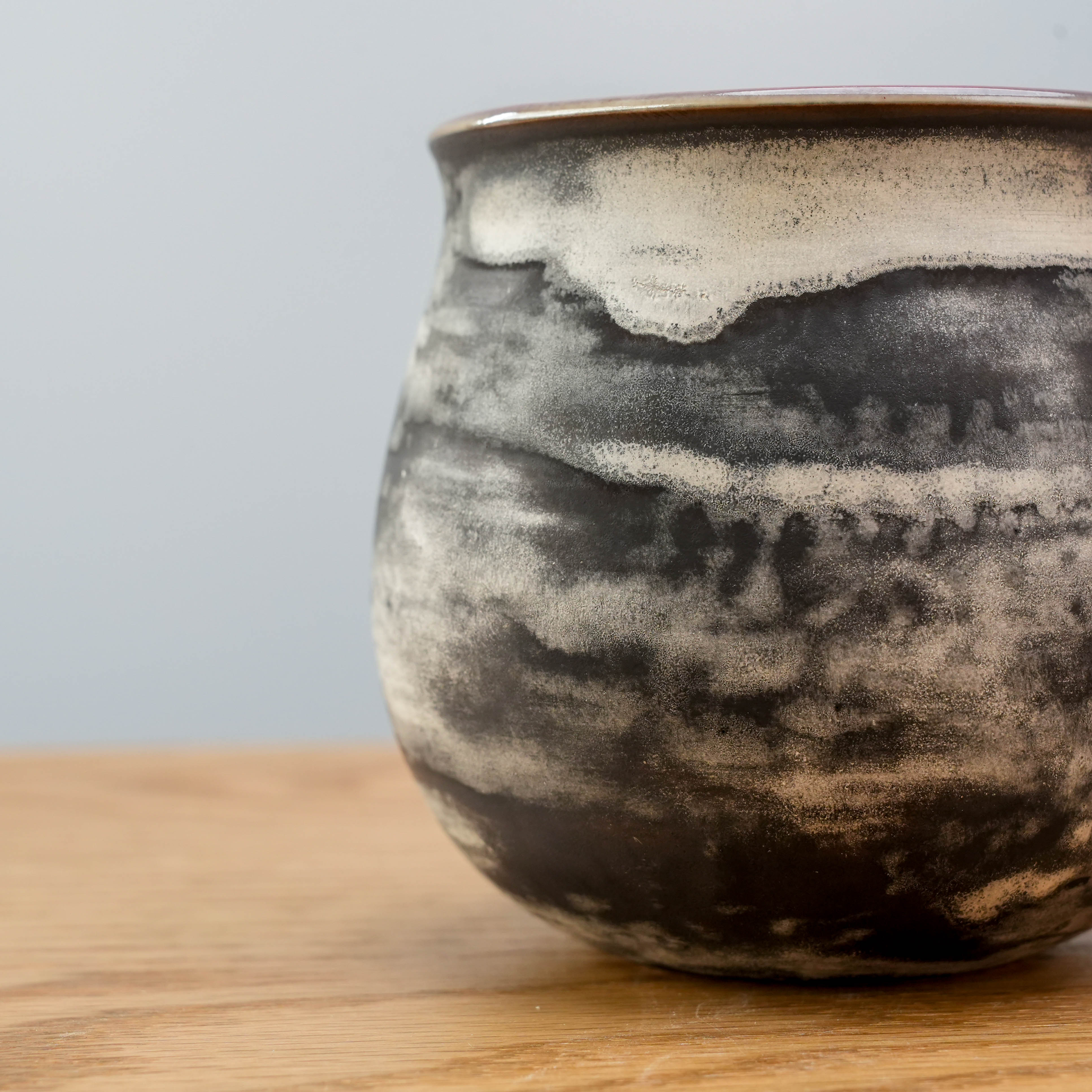 Close-up of the Cloudy Evening Cup’s textured black and cream glaze, showcasing artisanal ceramic detail for coffee lovers.
