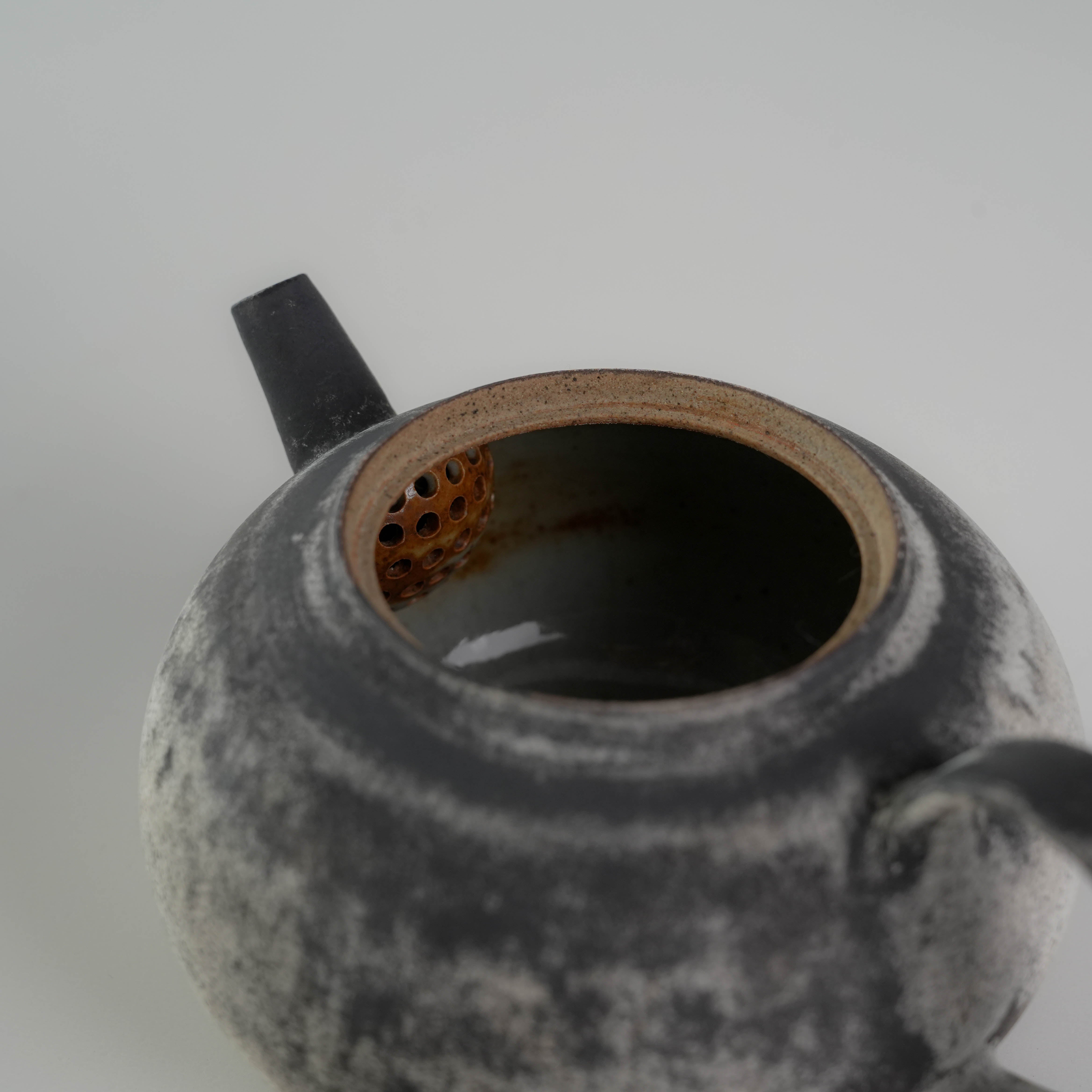 Interior view of Lonesome Studio Gushan Tea Set teapot showing built-in strainer and ceramic glaze details.