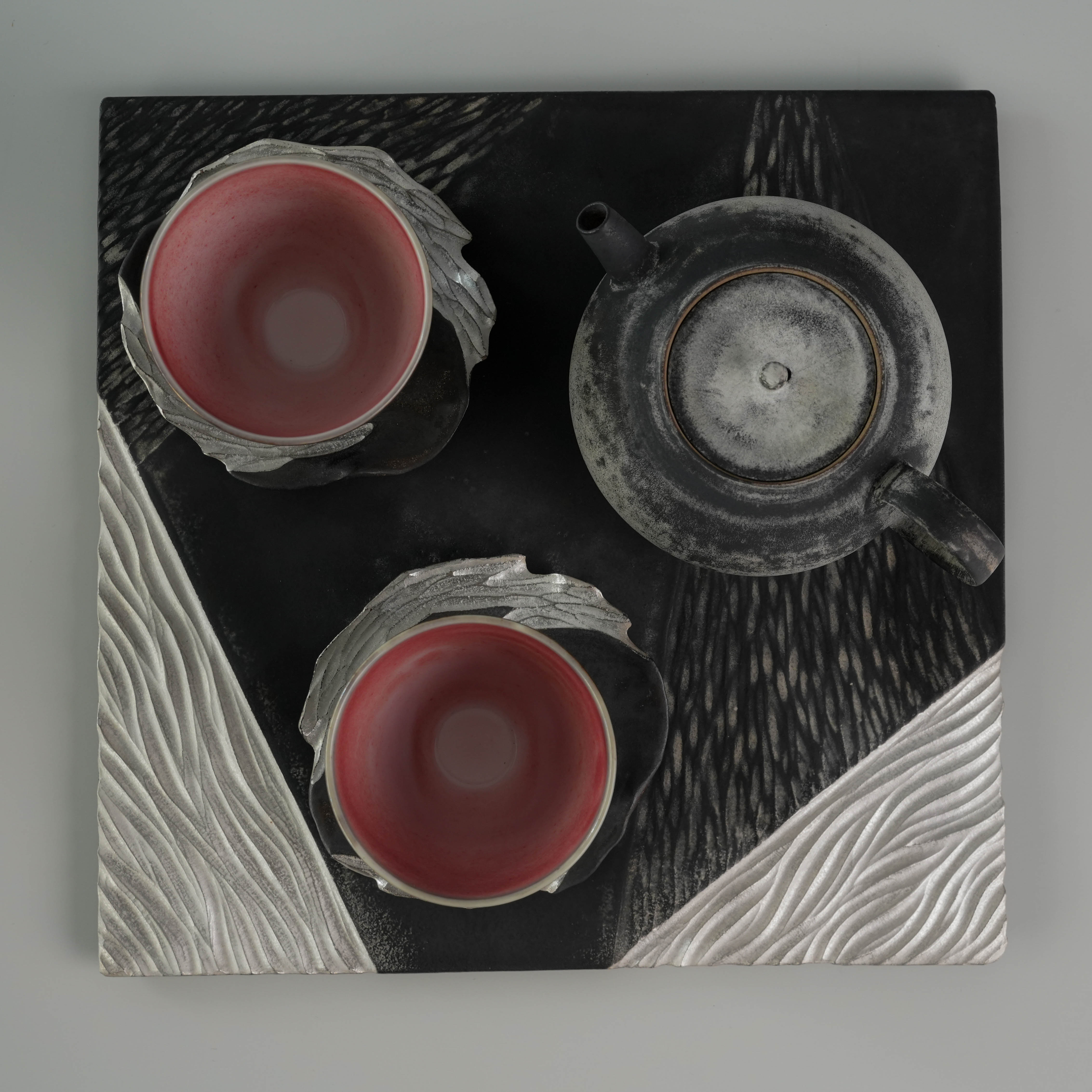 Top-down view of Lonesome Studio Gushan Tea Set with teapot and two cups on a geometric silver-glazed tray.