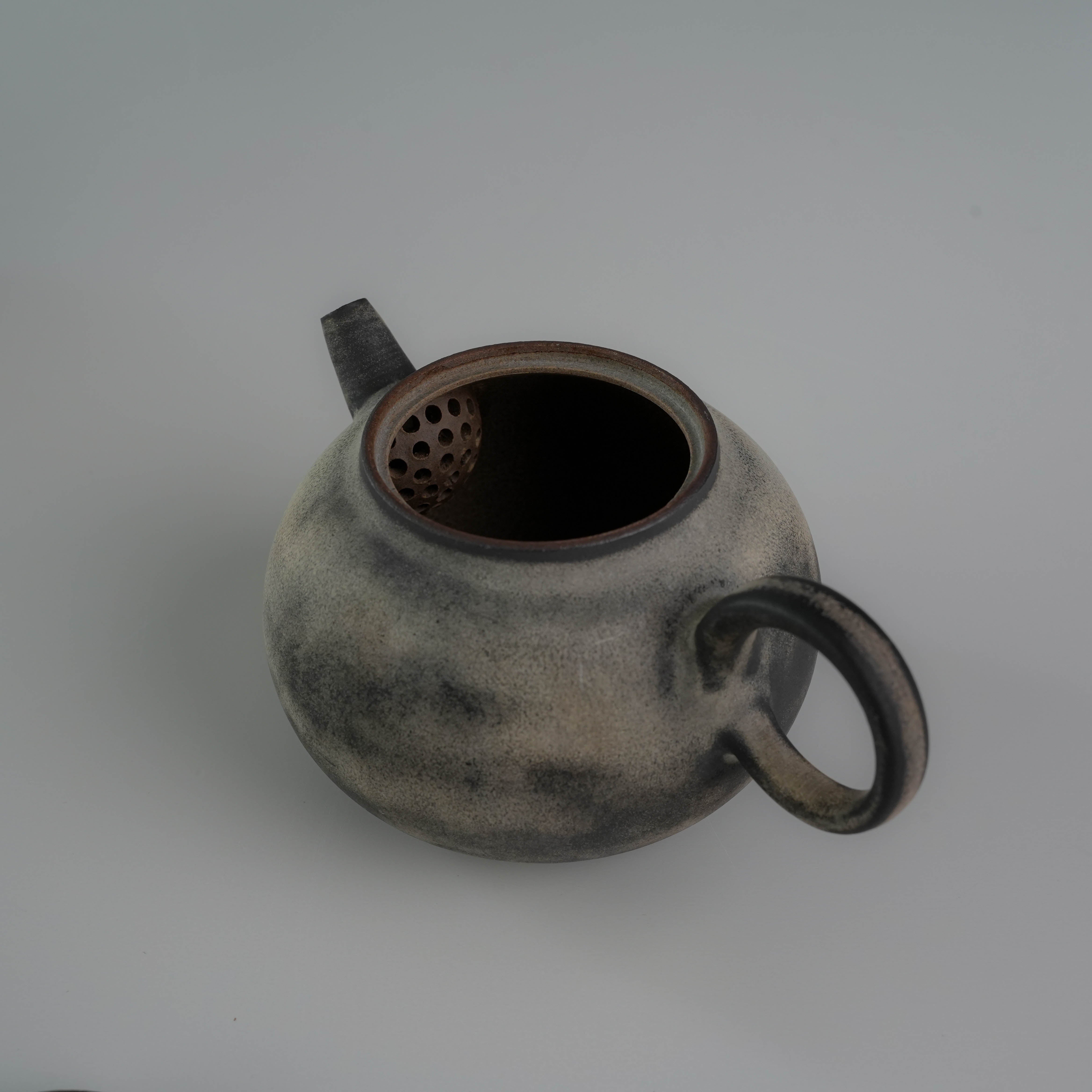 Interior view of Lonesome Studio Gushan Tea Set teapot showing ceramic strainer and handmade glaze details.