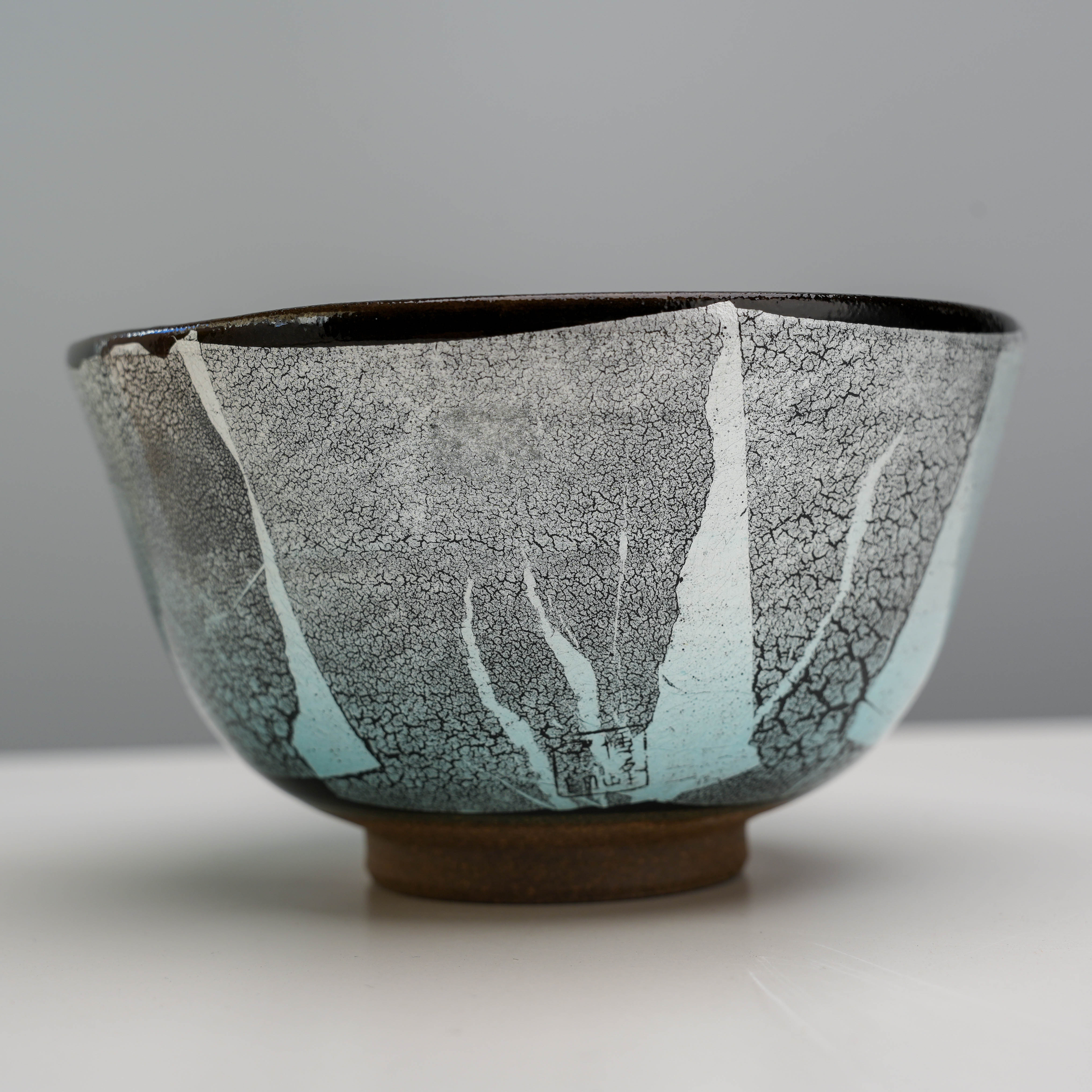 Close-up of Kutani Ware Matcha Bowl showcasing intricate silver foil crackle pattern over black and turquoise glaze.
