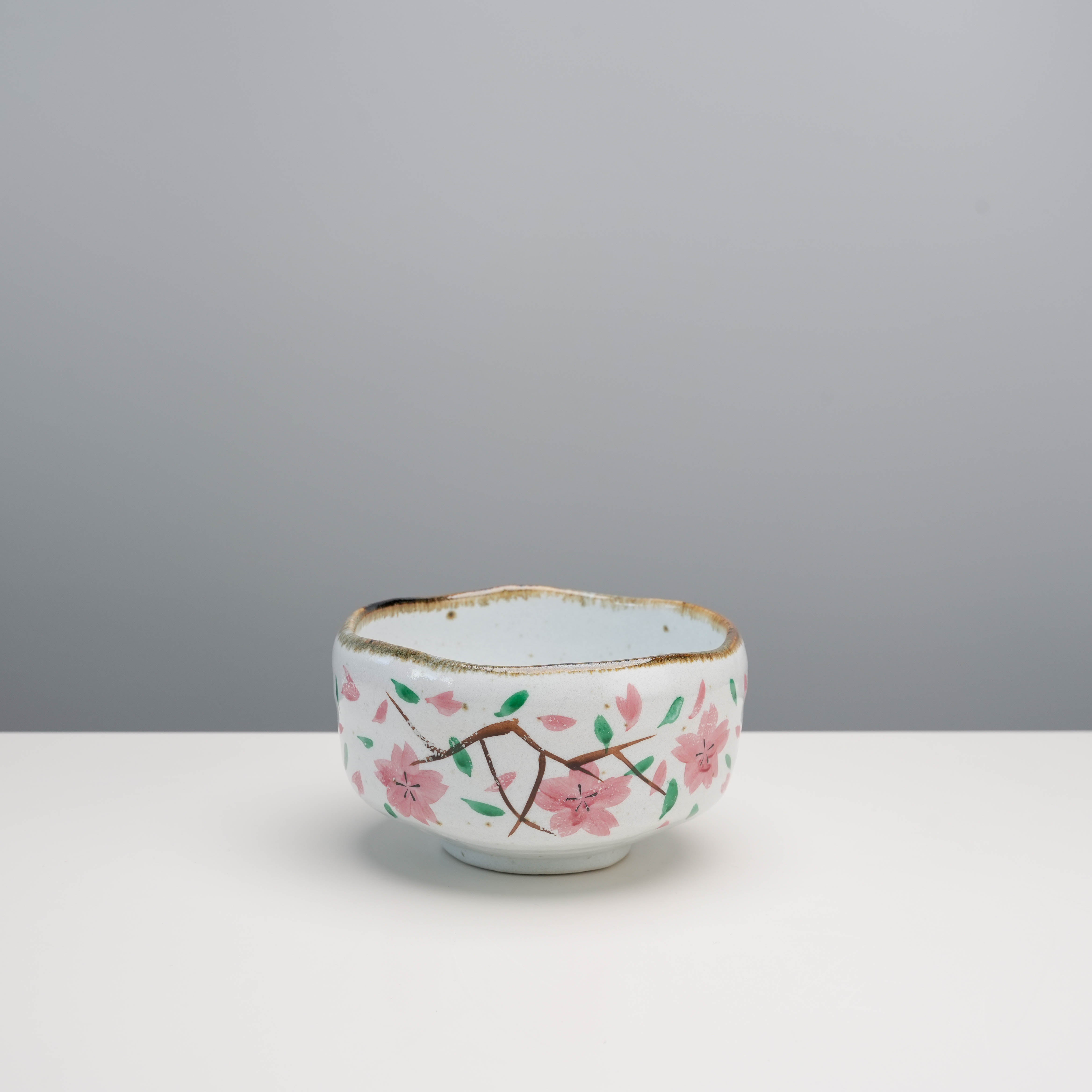 Mino Ware Cherry Blossom Matcha Bowl in earthy tones with hand-painted pink sakura flowers, ideal for traditional tea ceremonies.