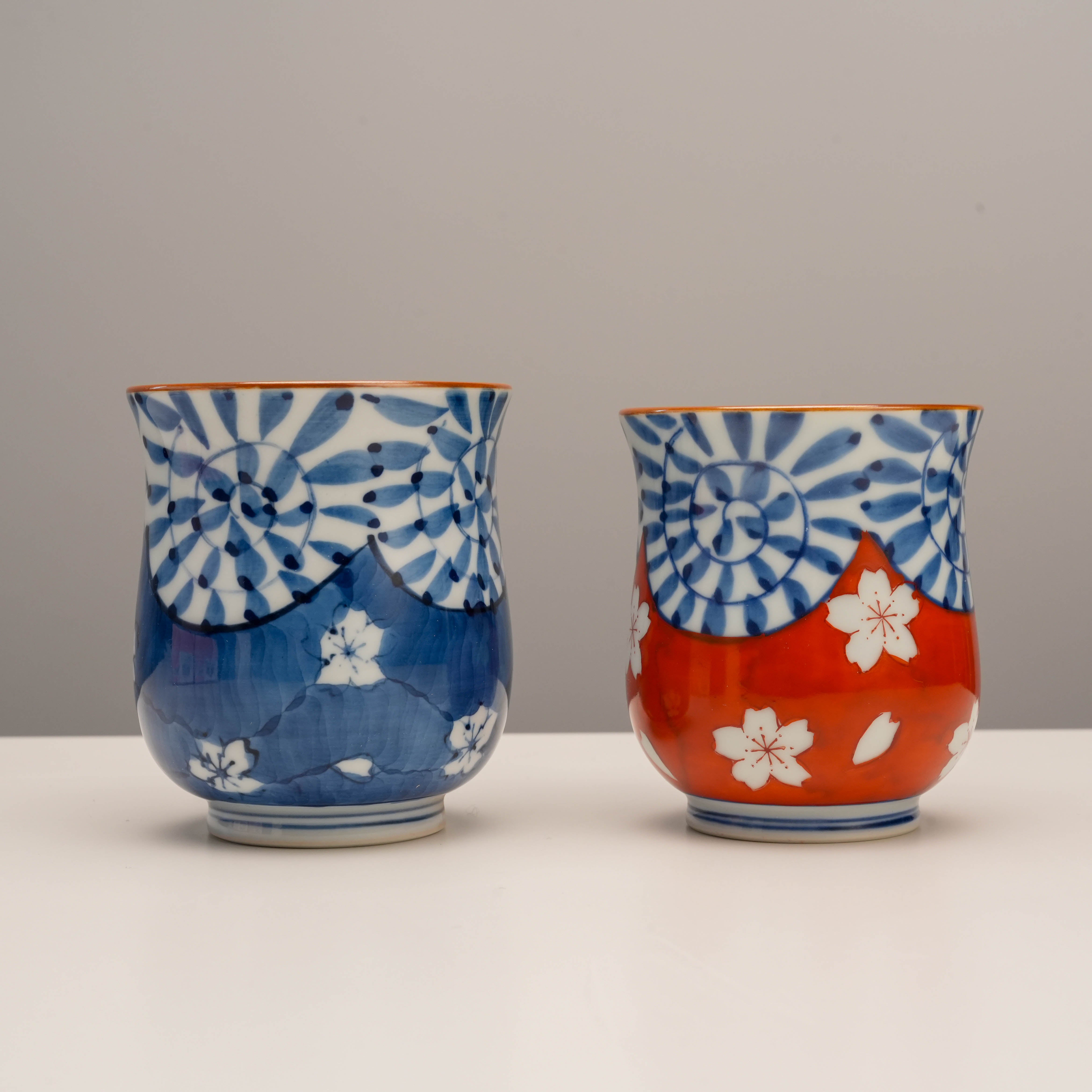 Arita Ware Tea Cup set featuring hand-painted arabesque and cherry blossom motifs in blue and red. Durable Japanese porcelain for tea lovers.